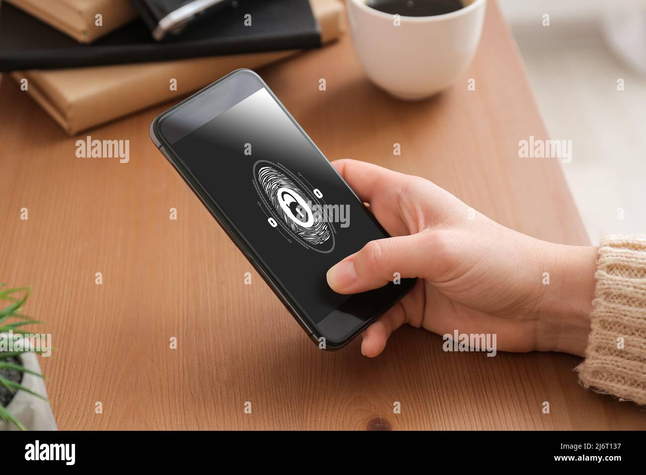 Frau mit Smartphone, die Fingerabdruckscanner verwendet, um sich in das persönliche Konto einzuloggen, Nahaufnahme Stockfoto