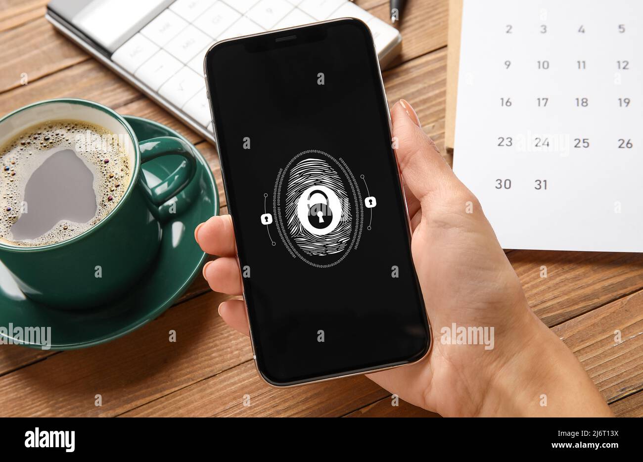 Frau mit Smartphone, die Fingerabdruckscanner verwendet, um sich am Arbeitsplatz in Nahaufnahme bei einem persönlichen Konto anzumelden Stockfoto