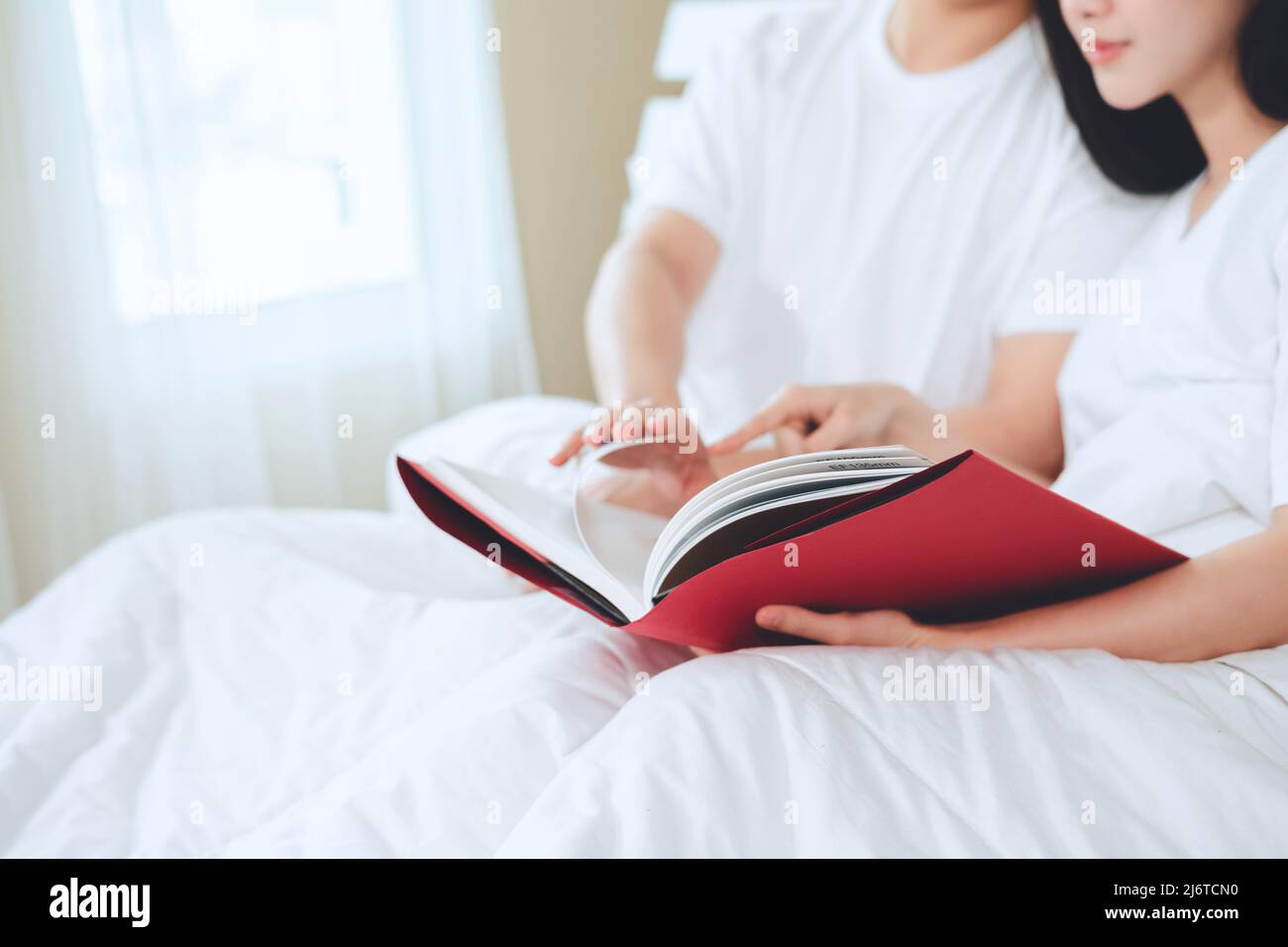 asiatische Paare planen für die Zukunft suchen Bücher, Kauf Lebensversicherung, Kauf von Häusern, Blick auf Hochzeitsfotos. Stockfoto