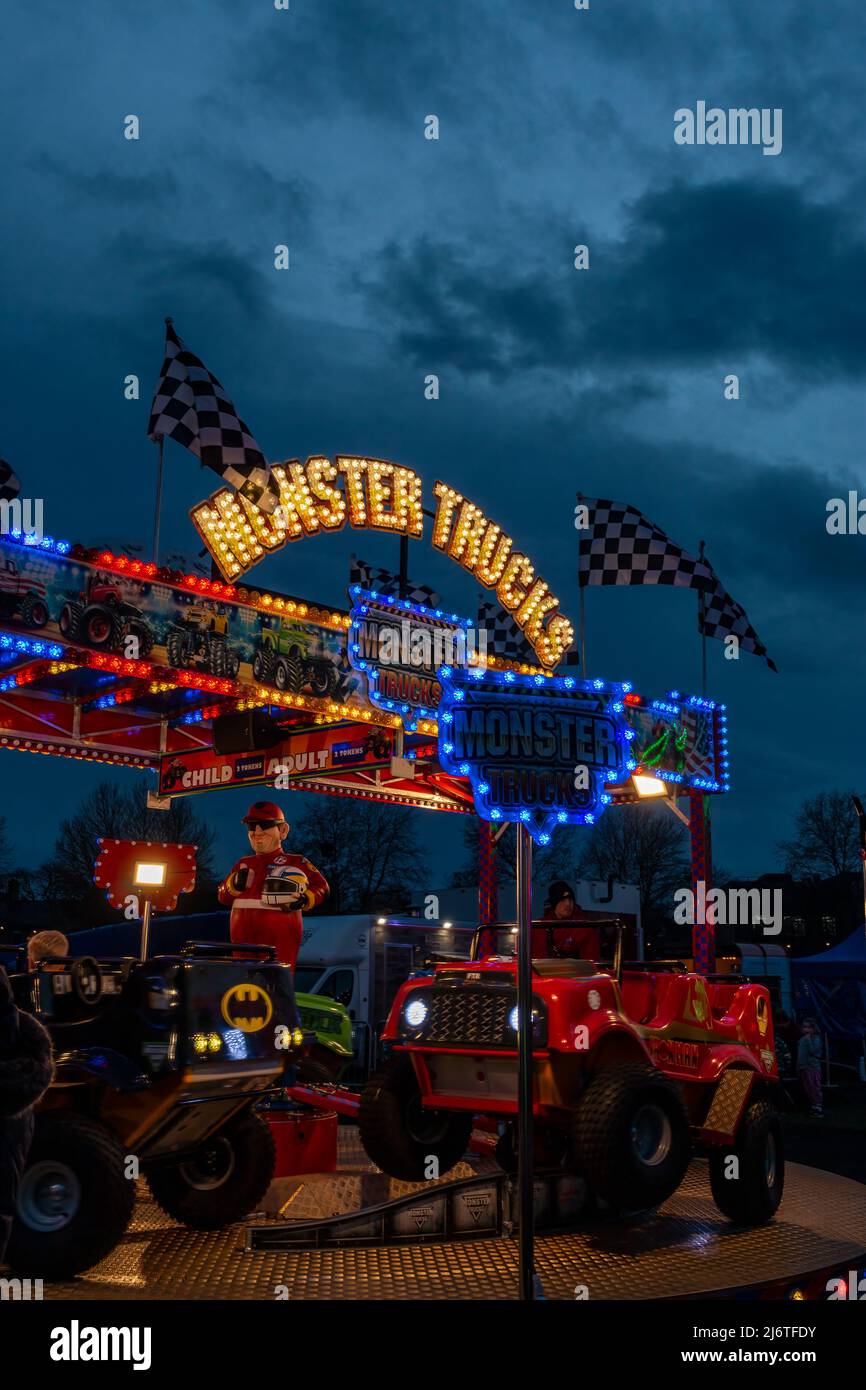 Die Lichter der Monster Trucks Fairground Ride erhellen den Nachthimmel. Stockfoto