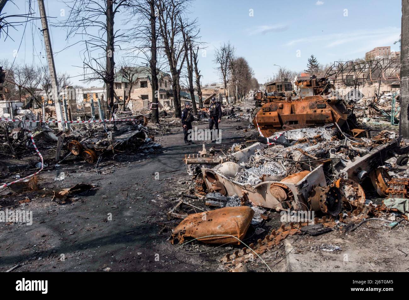 Zwei Polizisten kommen in einer Straße in Bucha an zerstörten und verbrannten Panzern vorbei. Bucha, eine Stadt am Rande der ukrainischen Hauptstadt Kiew, wurde etwa einen Monat lang von russischen Soldaten kontrolliert. Ihre Befreiung am 31. März enthüllte einige der grausamsten Gräueltaten, die russische Soldaten während der Besatzung verübt hatten. Gebäude wurden zerstört und Häuser geplündert. In Bucha Straßen, Gebäuden und Massengräbern wurden Leichen gefunden. (Foto von Rick Mave / SOPA Images/Sipa USA) Stockfoto