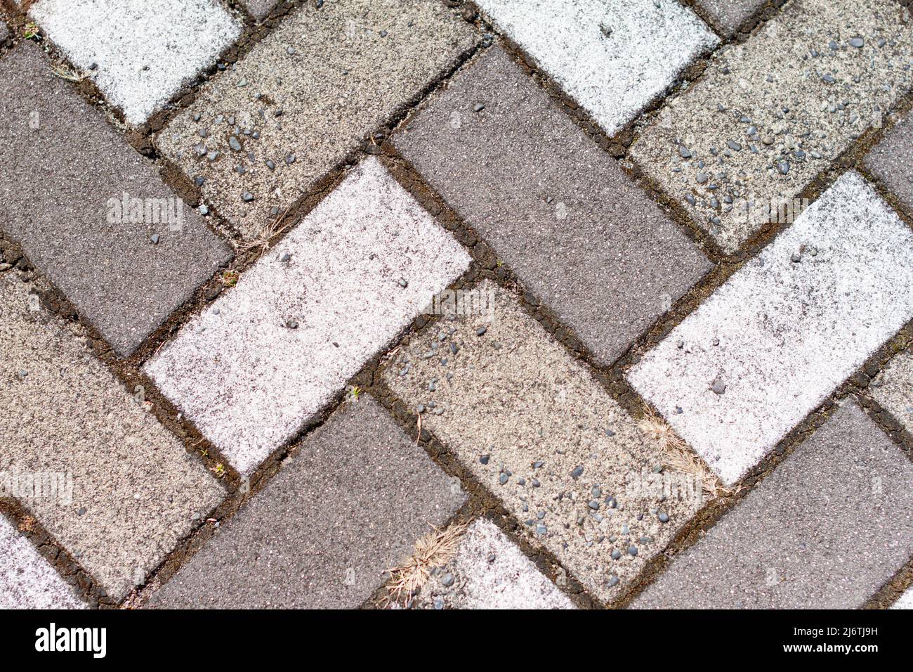 Nahaufnahme des Gehwegs mit rechteckigen weißen und grauen Fliesen in der Draufsicht gepflastert. Stockfoto