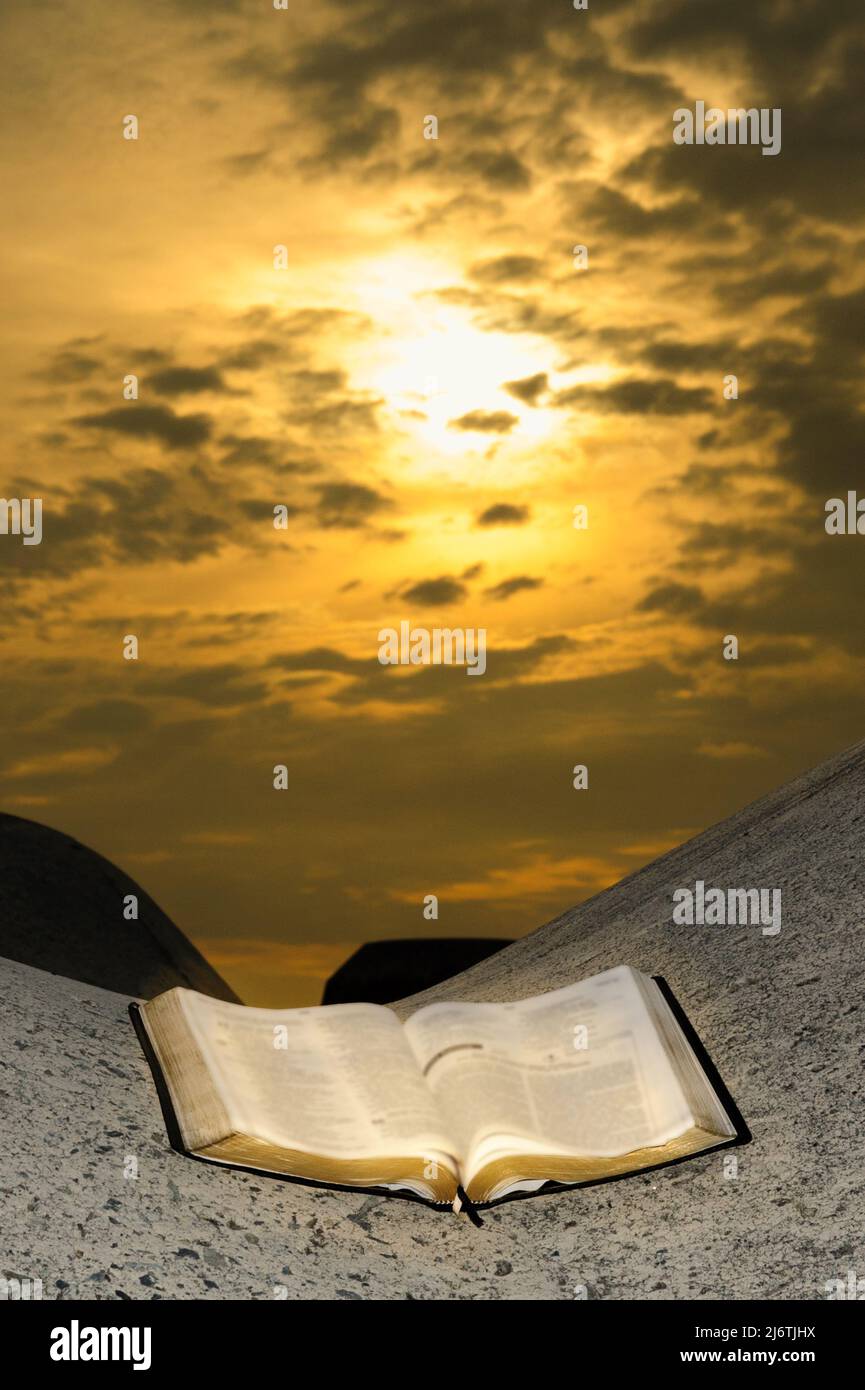 Öffnen Sie die Bibel auf einem Wellenbrecher mit atemberaubendem Sonnenaufgang. Stockfoto