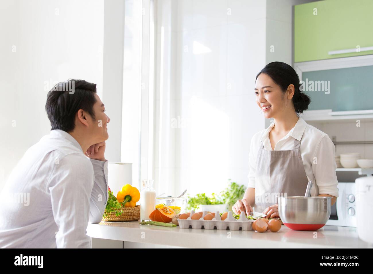 In der Familienküche kocht ein junges Paar gerne zusammen. Sie schauten einander tief in die Augen - Stockfoto Stockfoto