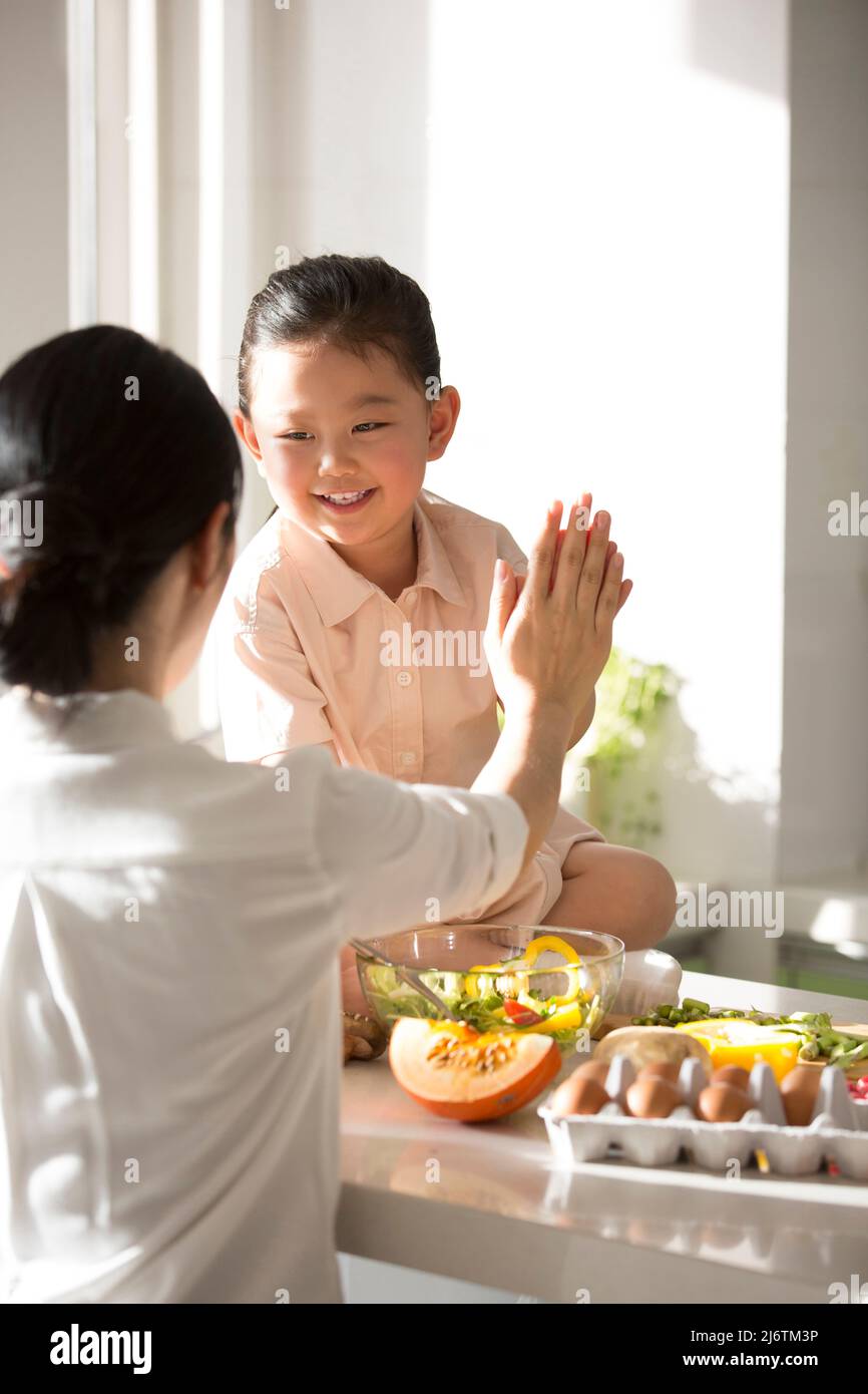 Familienküche Abstammung. Junge Mutter in der Küche mit ihrem Kind, ermutigte ihre Tochter und gab ihr eine hohe fünf. - Stock Foto Stockfoto