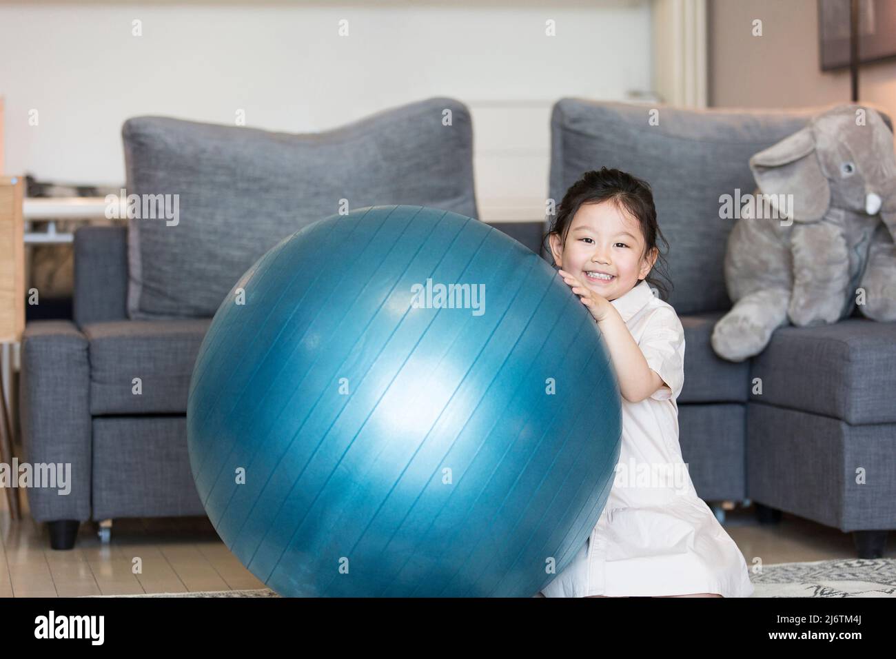 Ein schüchternes kleines chinesisches Mädchen, das im Wohnzimmer der Familie eng spielt - Stock photo Stockfoto