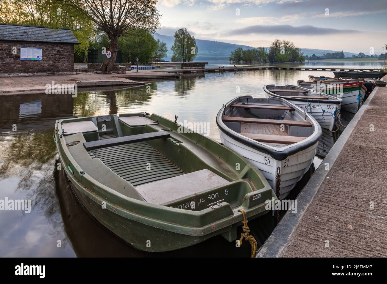 Boote, die an den Anlegesteg am Llangorse Lake, Brecon Beacons National Park gebunden sind. Aufgenommen kurz nach Sonnenaufgang. Stockfoto