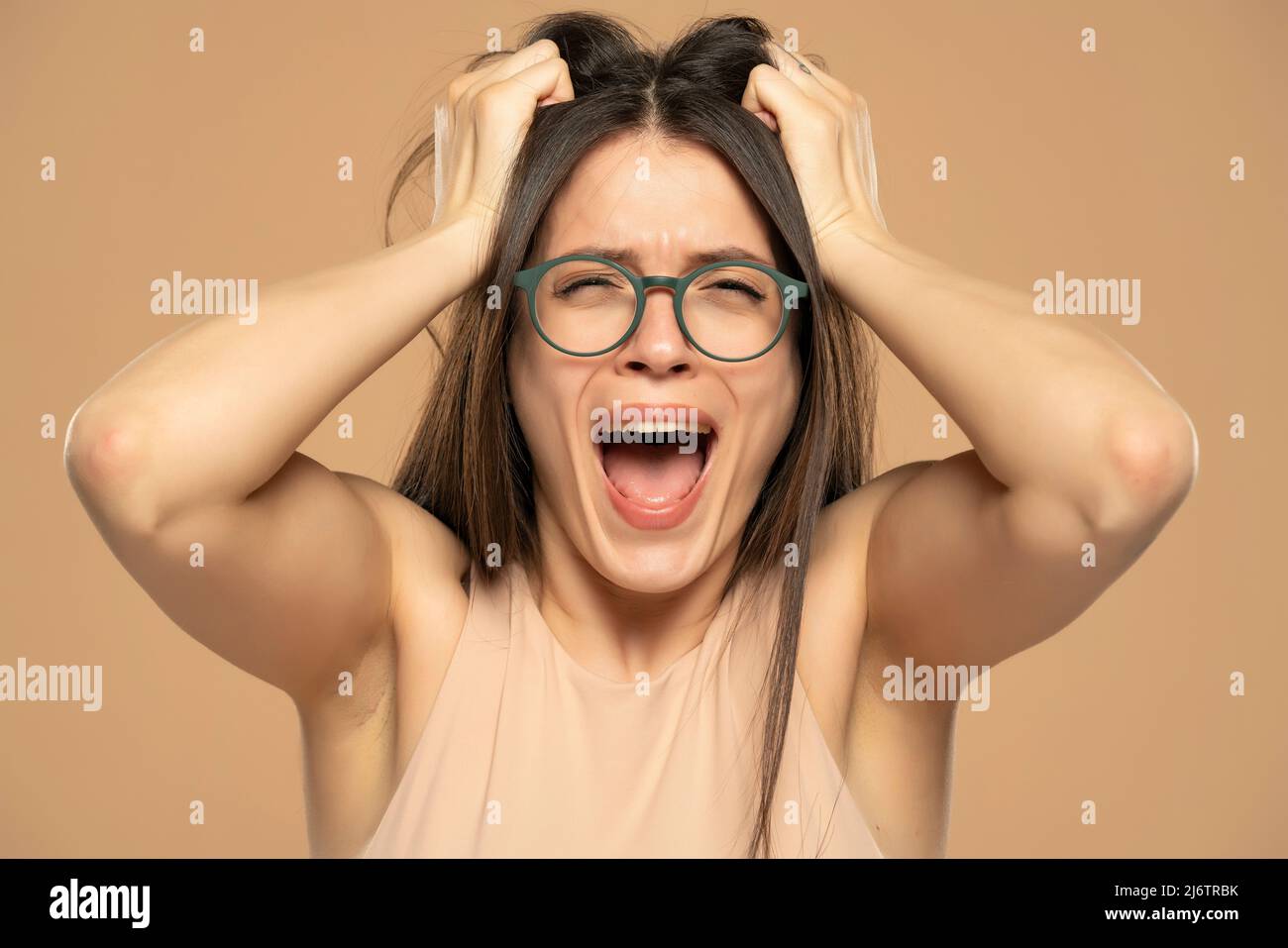Nahaufnahme Porträt gestresst frustriert Frau mit Brille schreiend isoliert auf beigem Hintergrund. Negative menschliche Emotion Gesichtsexpression Reaktion atti Stockfoto