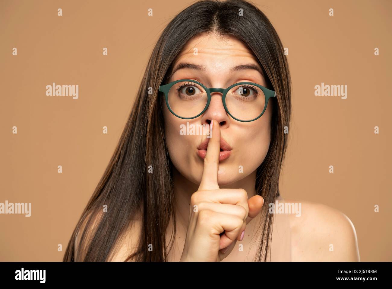 Porträt der jungen Frau Finger bedeckt Lippen Mund nicht sehen Kamera isoliert auf beige Farbe Hintergrund zu sagen. Stockfoto