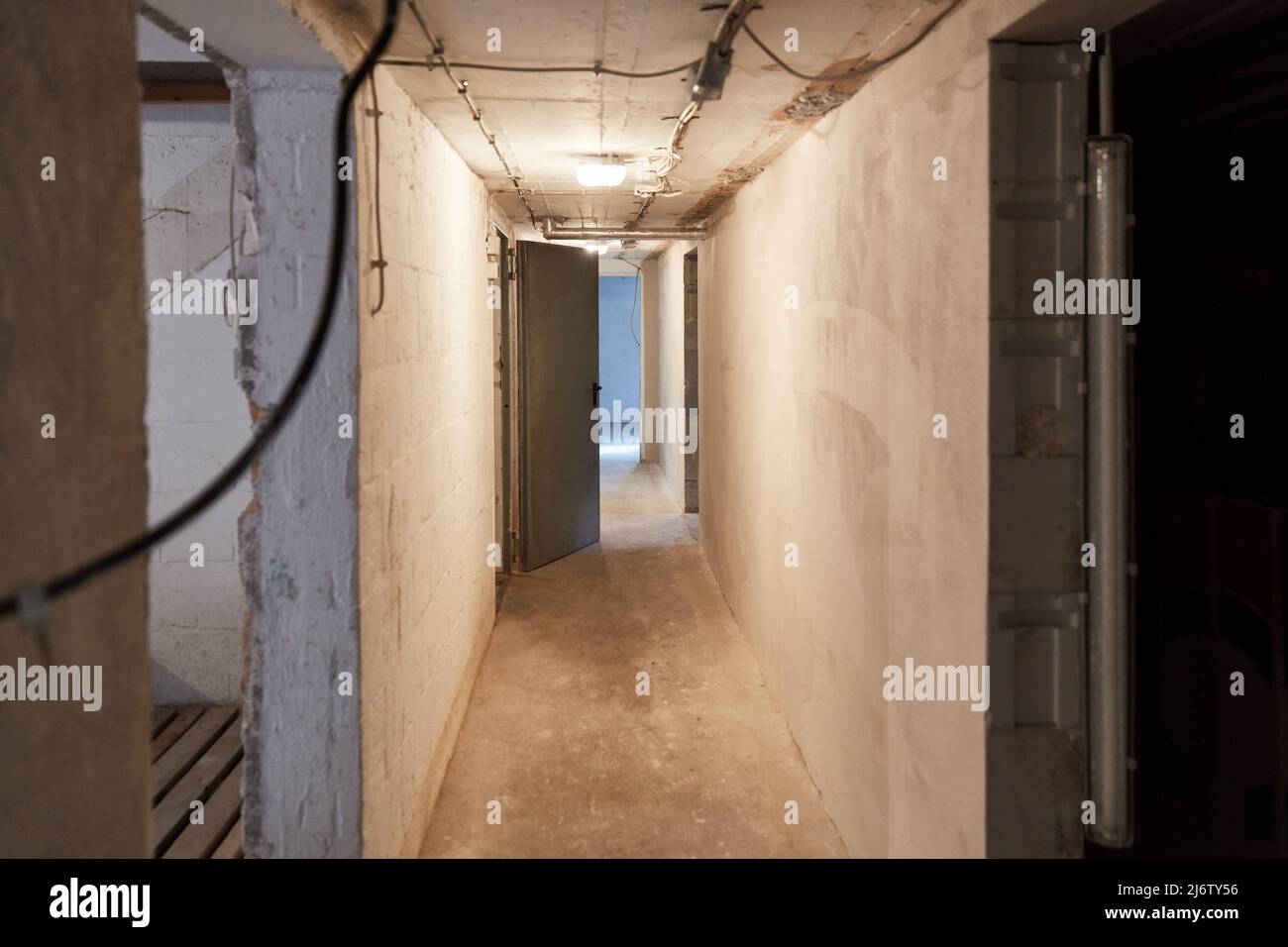 Verputzter enger Flur oder Flur im Keller mit Deckenleuchte und Tür Stockfoto