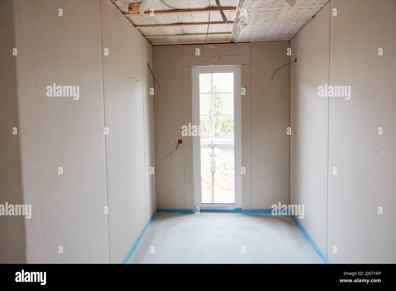 Kleiner, enger Raum mit einer schmalen Terrassentür in einem Neubau eines Hauses mit einem frischen Estrich Stockfoto