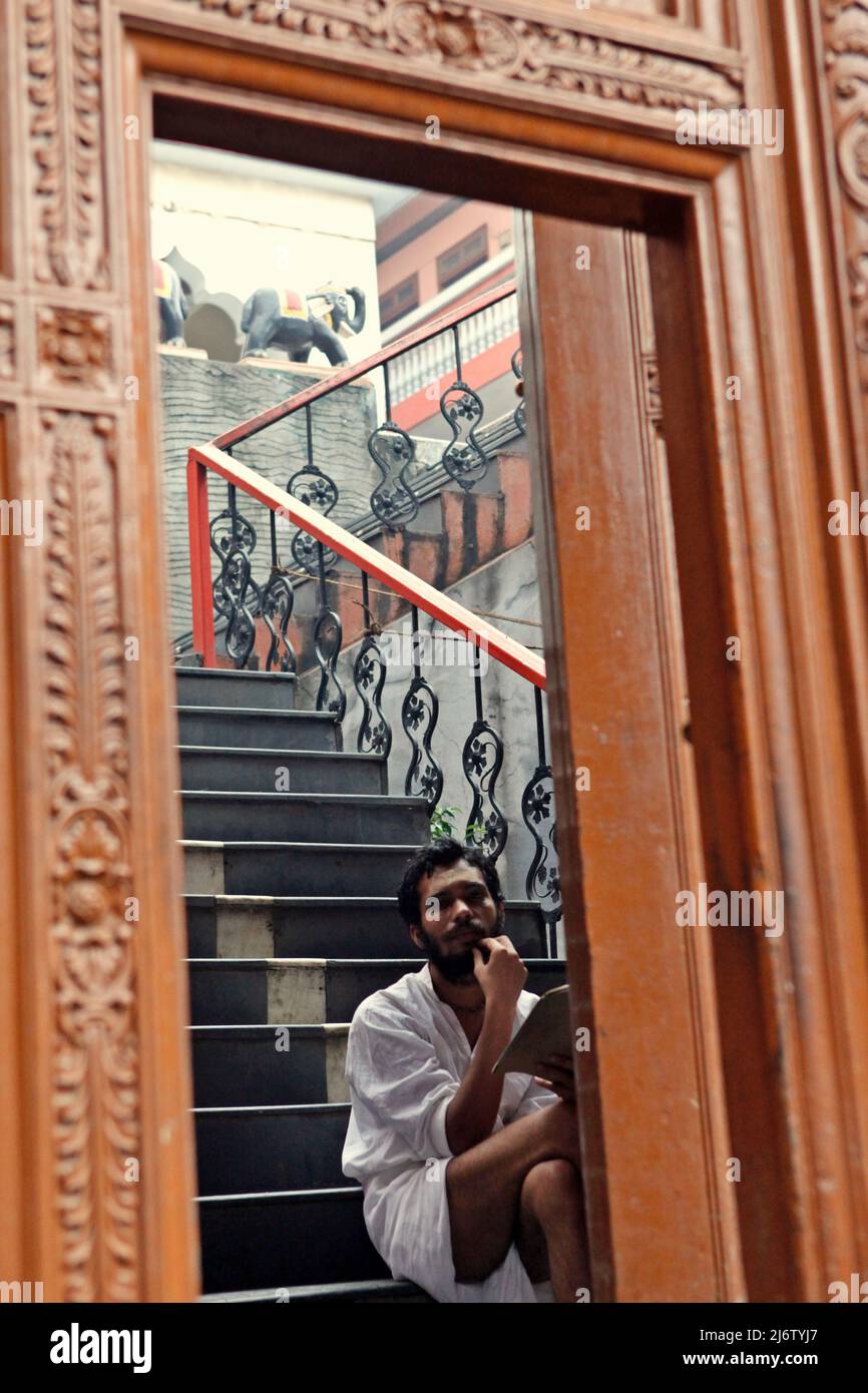Glasspiegelung eines Shri Satuwa-Anhängers, der auf der Treppe des Shri Satuwa Baba Ashram in Varanasi, Uttar Pradesh, Indien, sitzt. Stockfoto