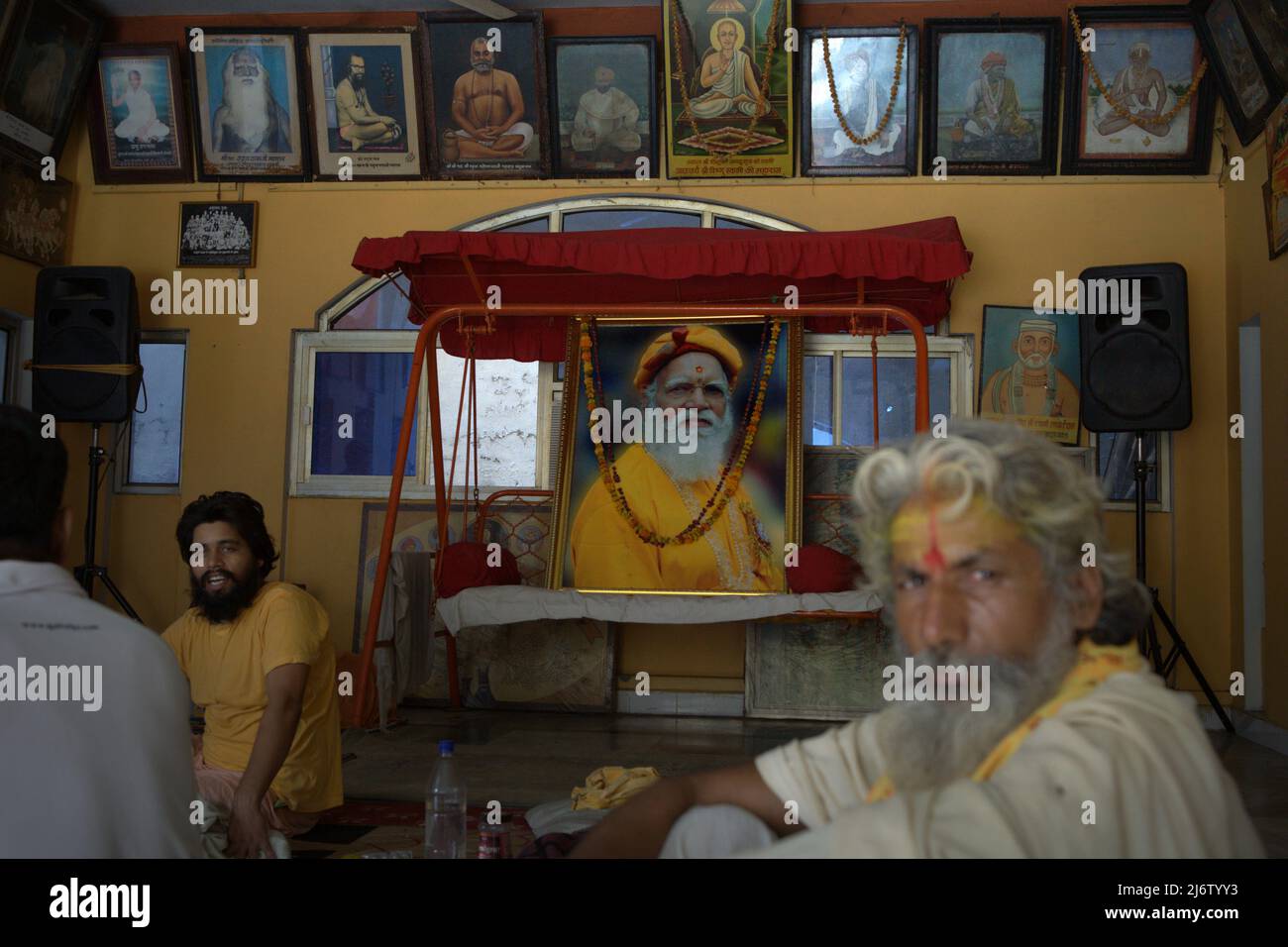 Porträt eines Sadhu-Anhängers vor einem Hausmeister und großes gedrucktes Foto von Shri Satuwa Baba Maharaj (1913-2012), dem sechsten Satuwa Baba, dem letzten spirituellen Führer im Ashram Shri Satuwa Baba in Varanasi, Uttar Pradesh, Indien. Stockfoto