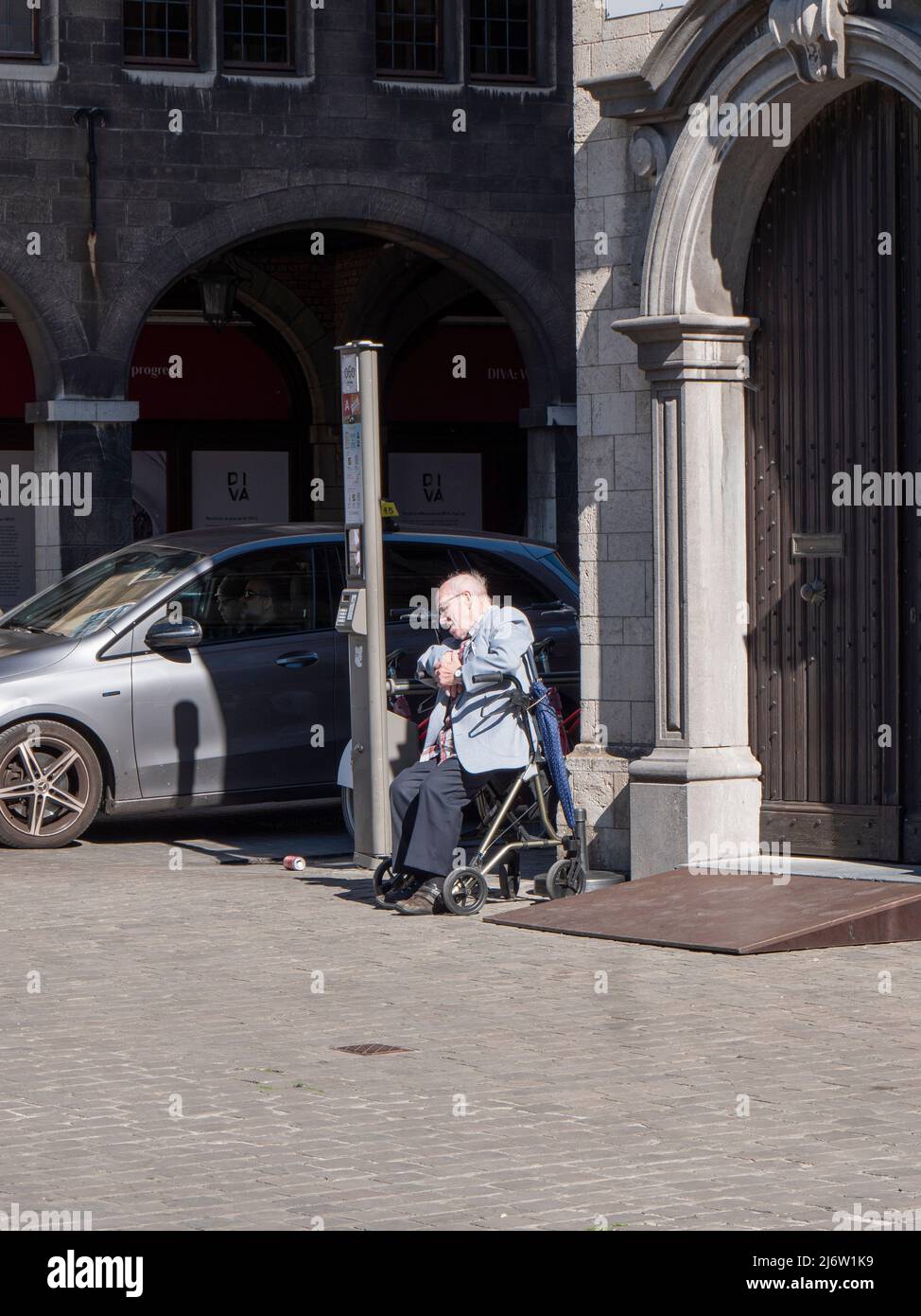 Antwerpen, Belgien, 17. April 2022, alter Mann sitzt auf seinem Spaziergänger in der Sonne und macht ein Nickerchen Stockfoto