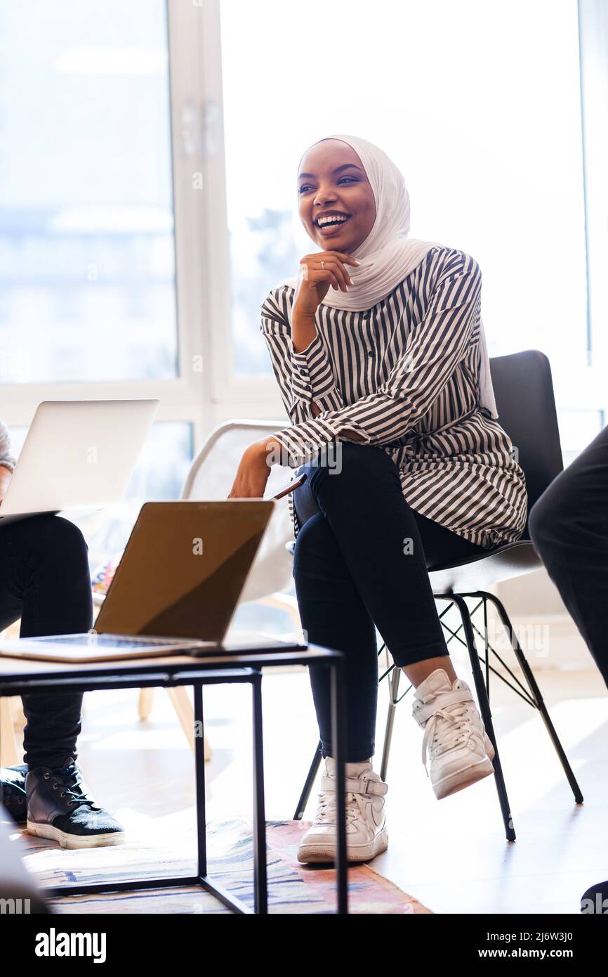 Junge erfolgreiche Frau beim Brainstorming bei einem kreativen Treffen. afroamerikanisch-muslimisches Mädchen lächelnd. Stockfoto