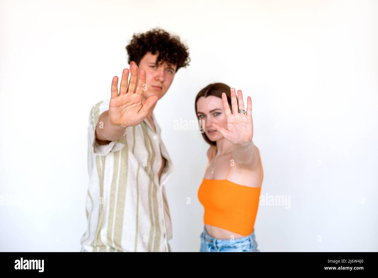 Porträt von jungen besorgt schönen Paar posiert auf weißem Hintergrund. Junger Mann und Frau mit offener Handfläche, fünf Zeichen. Stockfoto