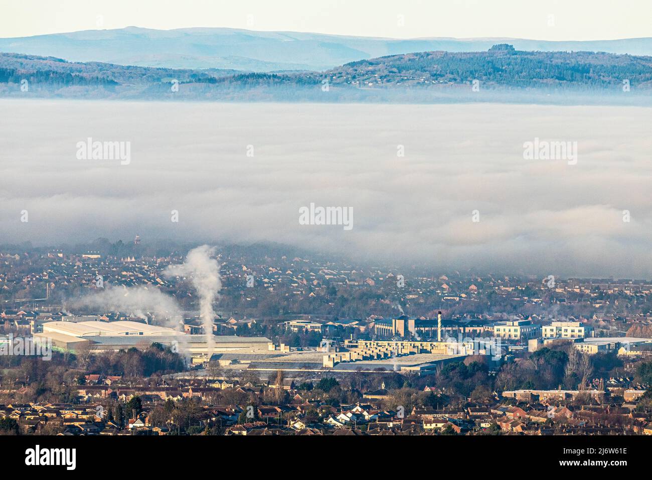 Eine Temperaturinversion, die Nebel verursacht, um die Stadt Gloucester, England, zu verdunkeln. Gloucester Business Park in Brockworth ist im Vordergrund und Mai Stockfoto