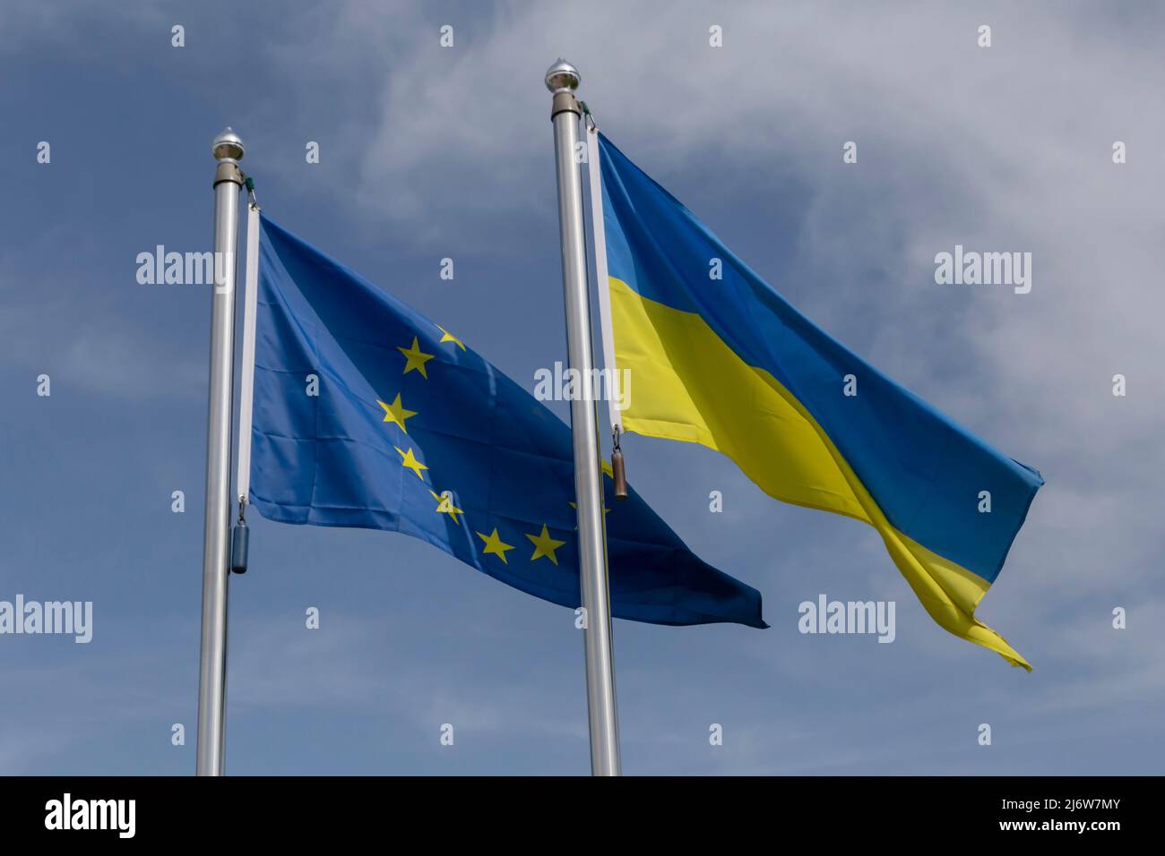 Flaggen der Europäischen Union und der Ukraine auf Fahnenmasten vor blauem Himmel mit weißen Wolken Stockfoto