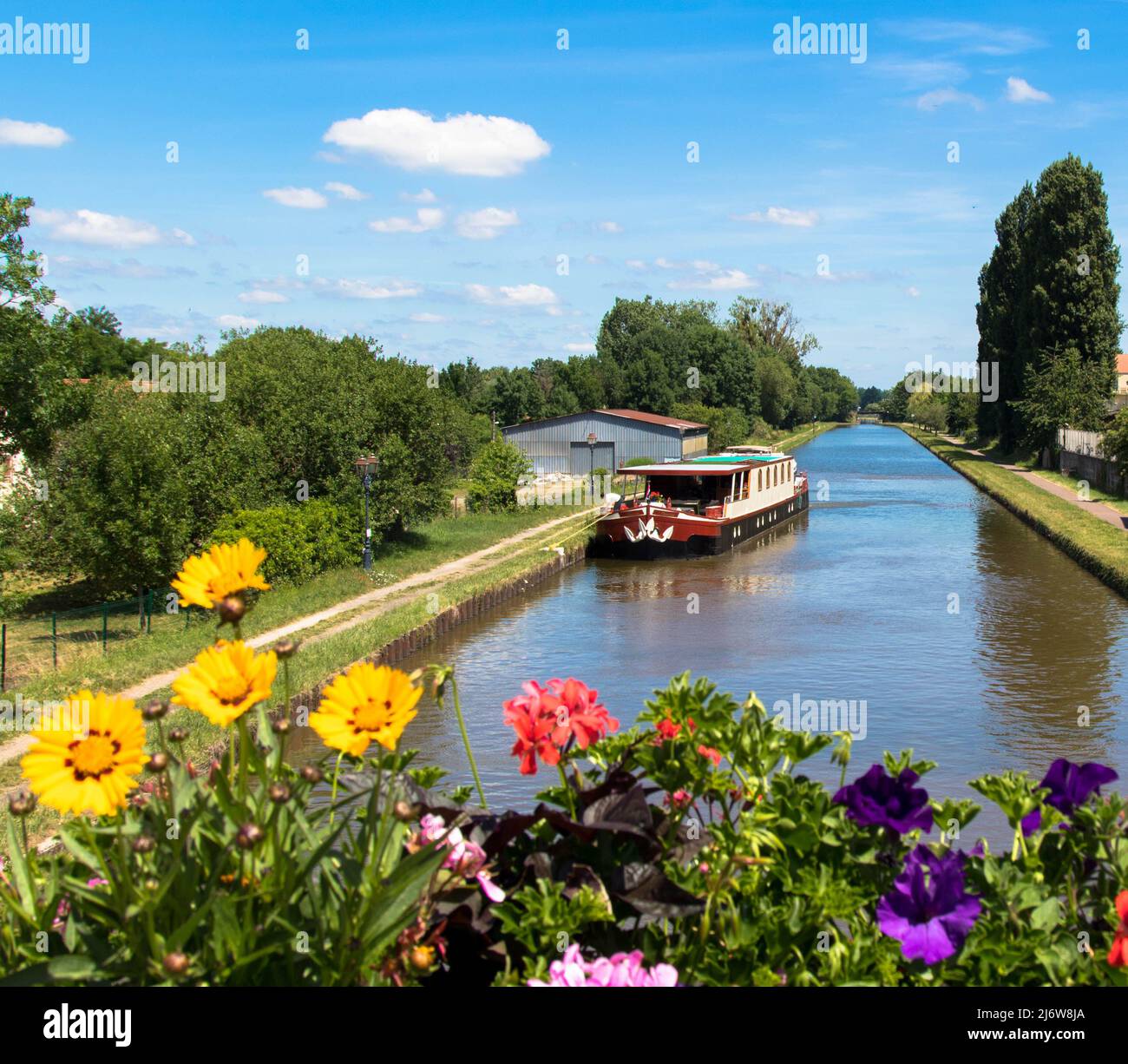 Mit dem gemieteten Hausboot auf dem Rhein-Marne-Kanal mit bunten Blumen im Vordergrund. Saverne Elsass Frankreich. Tourismus und Urlaub conept. Stockfoto