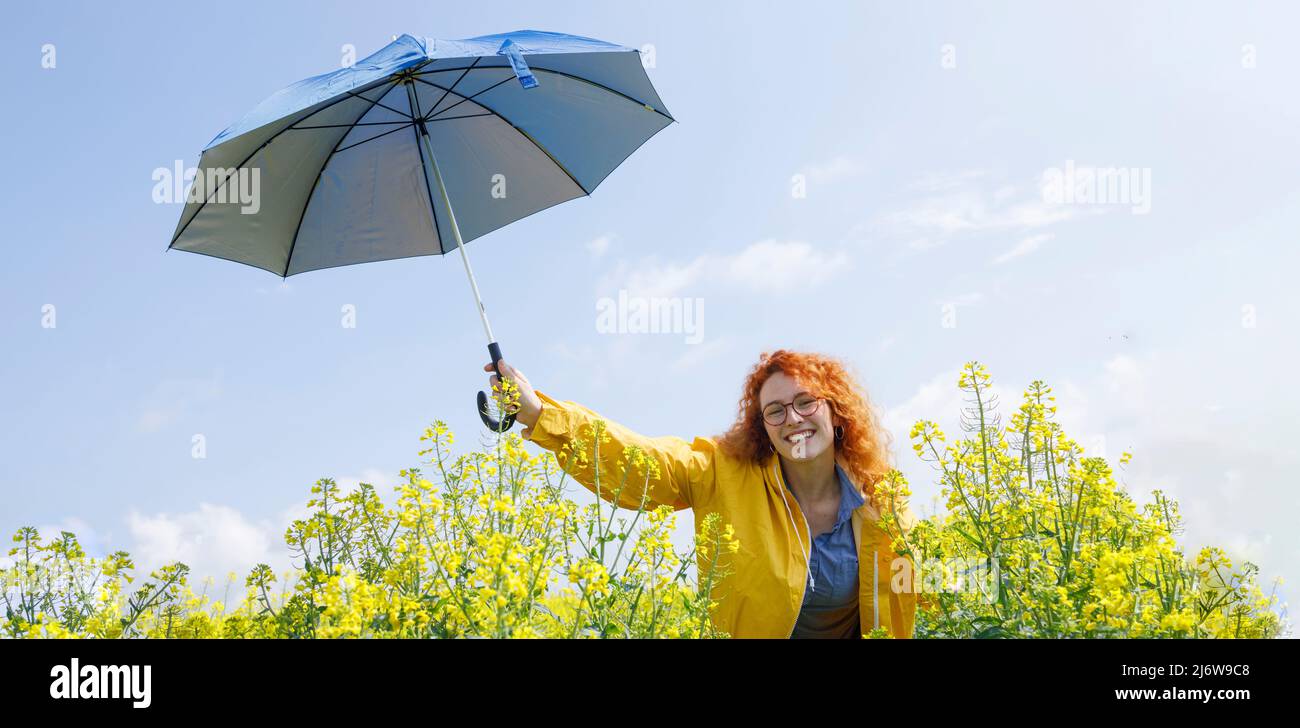 Junge Frau hält ihren Schirm und lächelt an einem Sommertag kurz nach dem Regen Stockfoto
