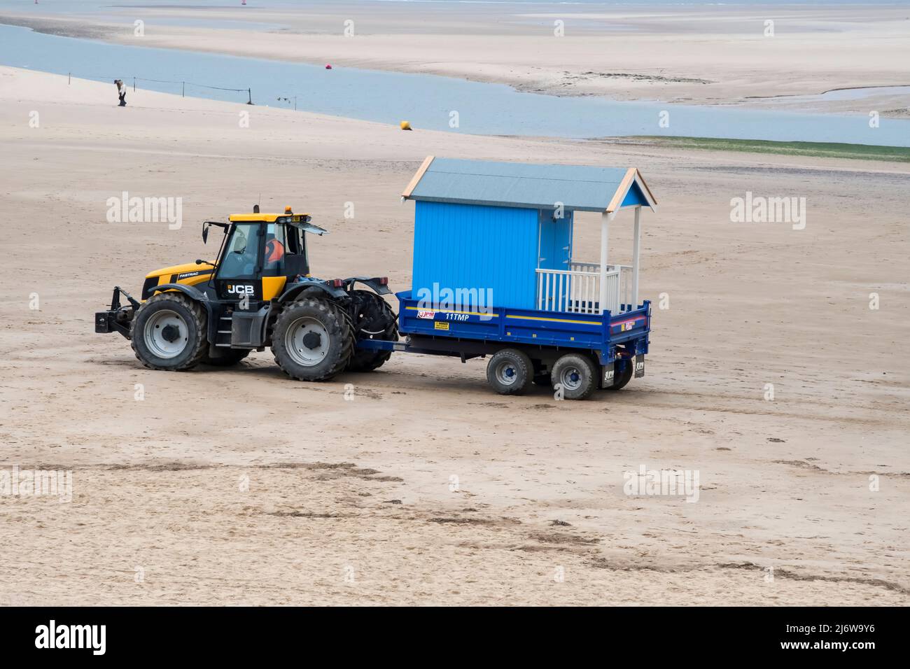 Eine neue Strandhütte, die von einem Traktor für die Installation am Strand von Wells-next-the-Sea, North Norfolk, geliefert wird. Stockfoto