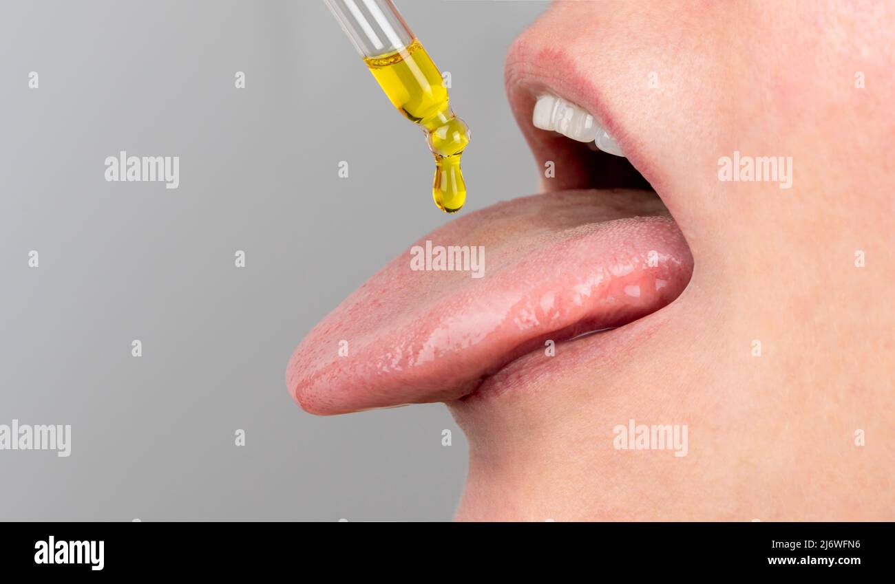 Zungenöl Pipette. Pflanzliche alternative Medizin und Nahrungsergänzungsmittel Frau, die CBD Hanföl Tropfen im Mund von Tropf. Medizinisches Cannabisöl. S Stockfoto