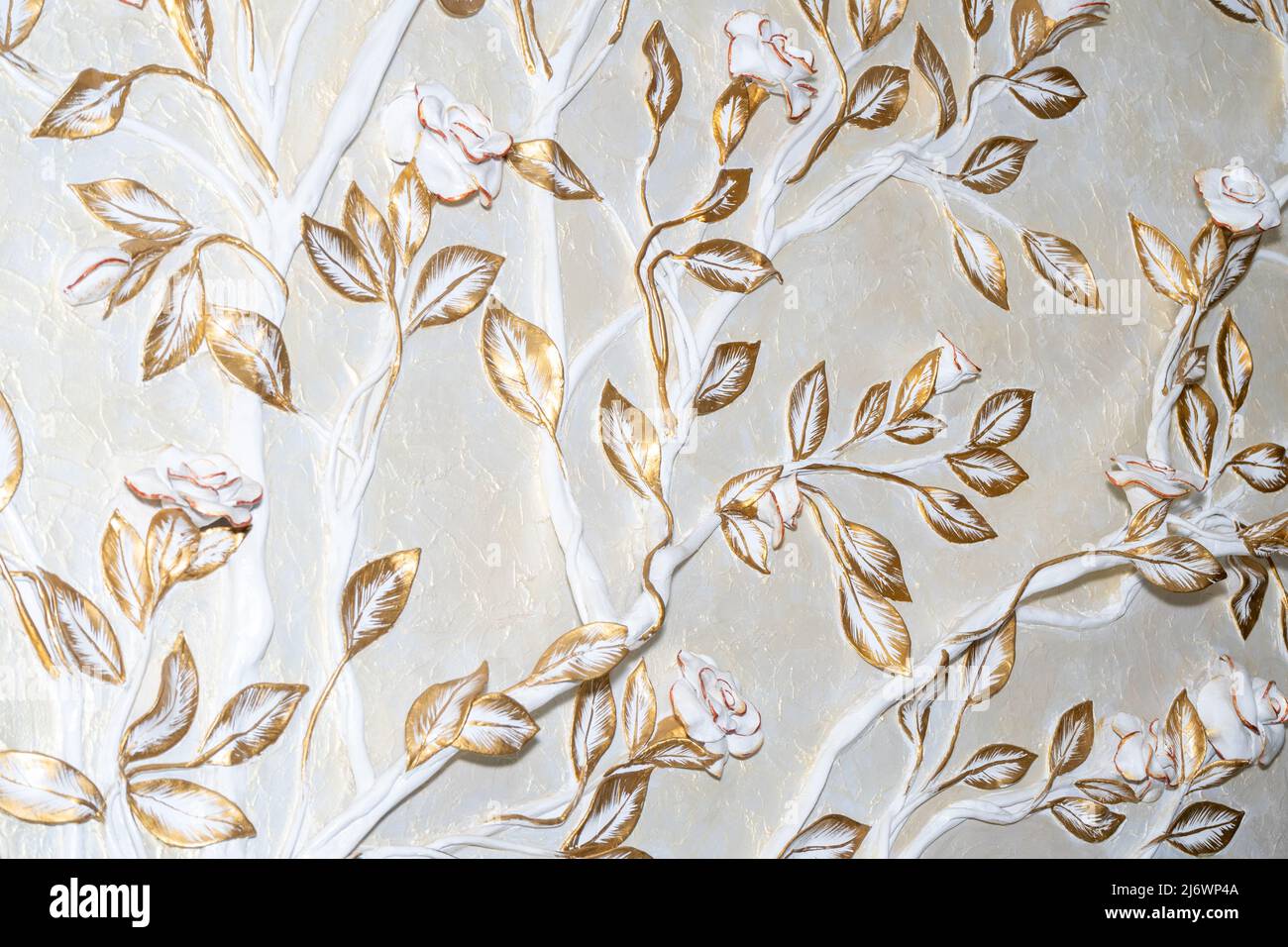 Zimmerdekoration. Blumen und goldene Blätter an der Wand gemeißelt Stockfoto