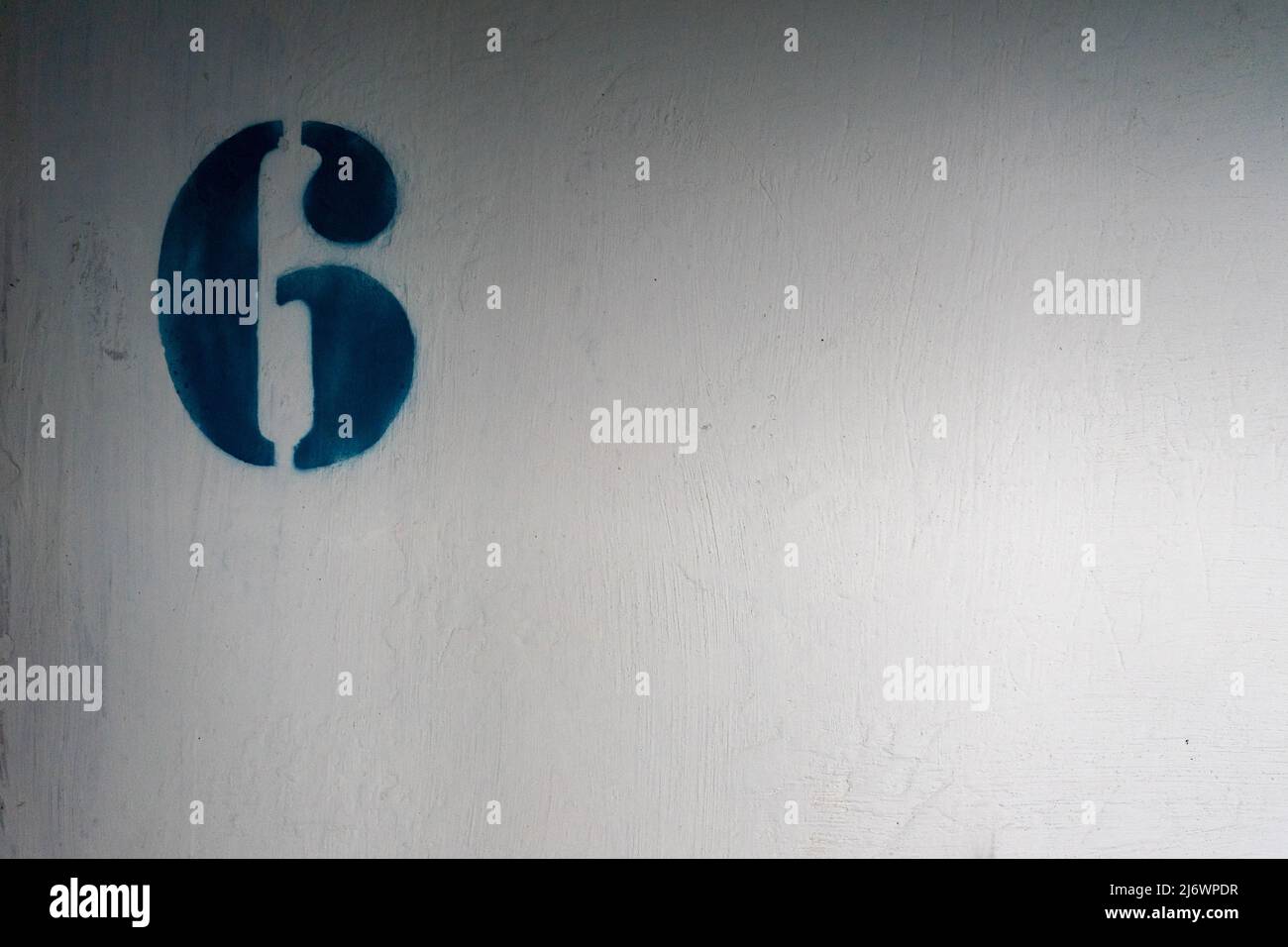 Nummer 6 an der weißen Wand. Der Name des Stockwerks in einem mehrstöckigen Gebäude Stockfoto