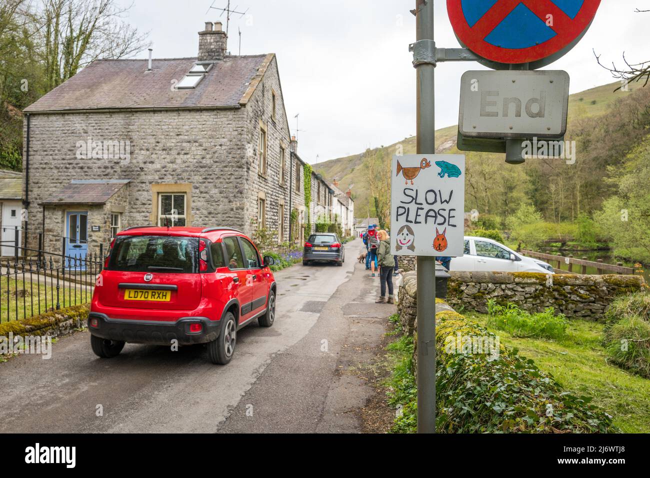 Spaziergänger, die mit handgefertigten Straßenschildern durch Litton Mill laufen, die den Autofahrer informieren, den Derbyshire Peak District National Park zu verlangsamen. Stockfoto