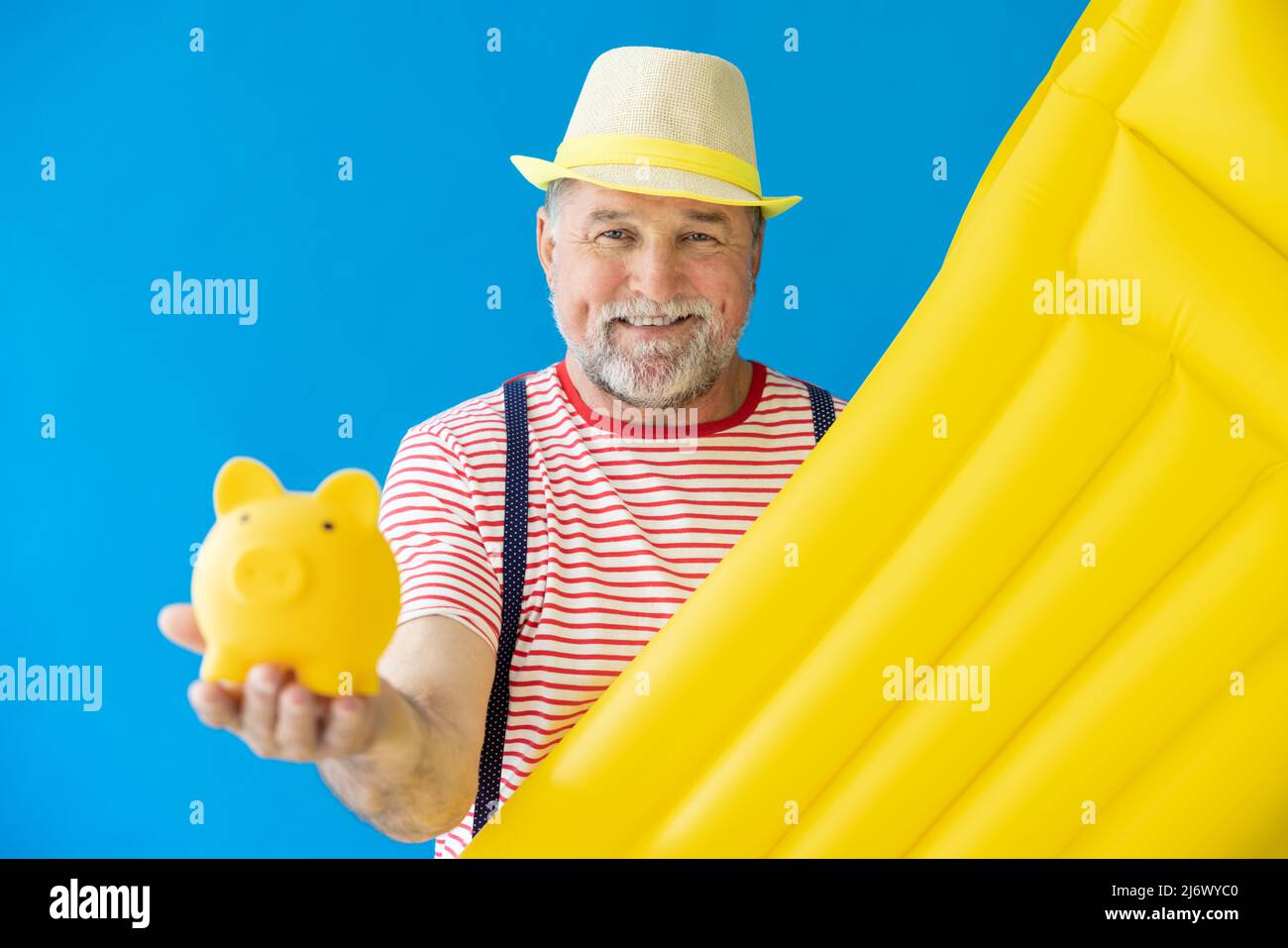 Glücklicher älterer Mann, bereit zu reisen. Person mit gelber Luftmatratze. Sommerurlaub und Urlaubskonzept Stockfoto