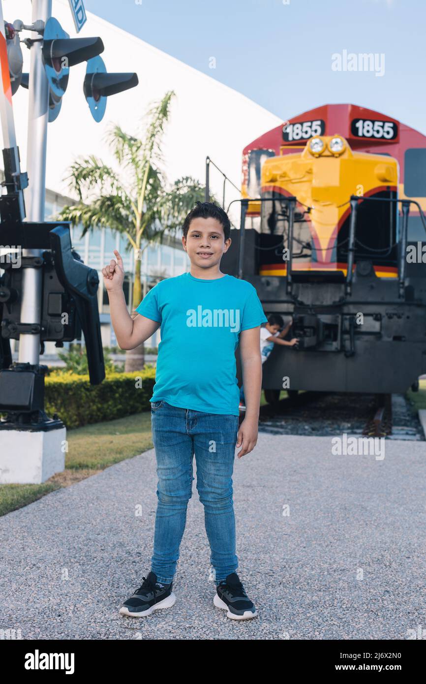 latino-Junge zeigt auf Eisenbahnschild und besucht Reliquien Stockfoto