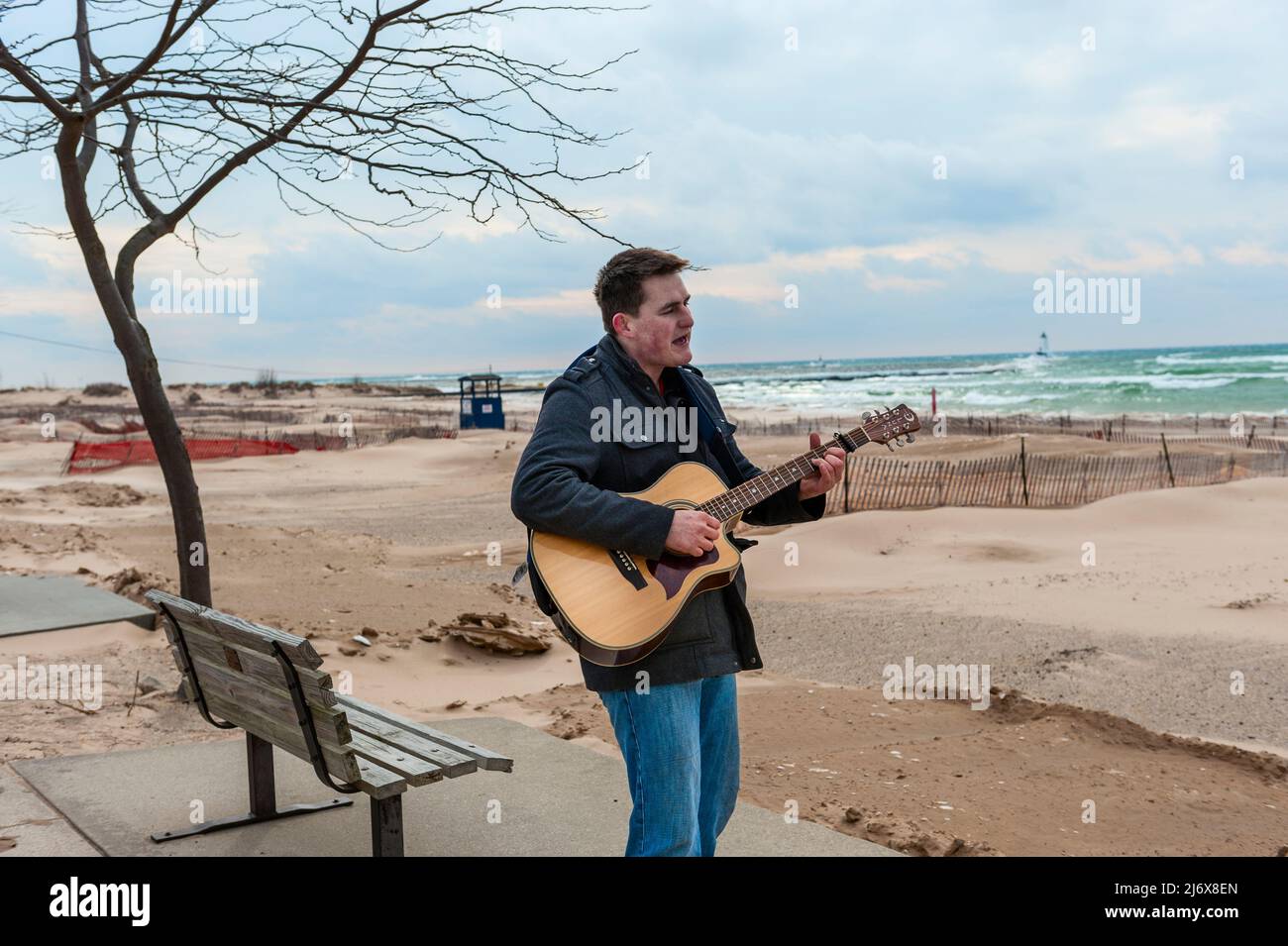 Straßenmusiker, der Gitarre spielt und am Strand von Stearns Park in Ludington, Michigan, USA, singt. Stockfoto