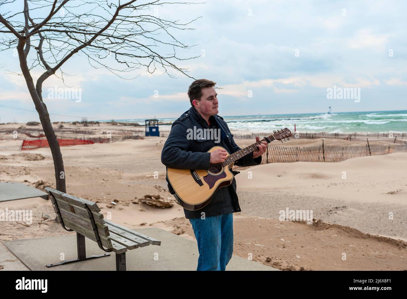 Straßenmusiker, der Gitarre spielt und am Strand von Stearns Park in Ludington, Michigan, USA, singt. Stockfoto