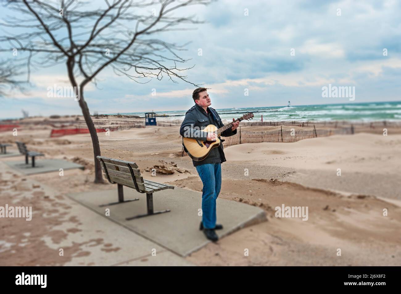 Straßenmusiker, der Gitarre spielt und am Strand von Stearns Park in Ludington, Michigan, USA, singt. Stockfoto