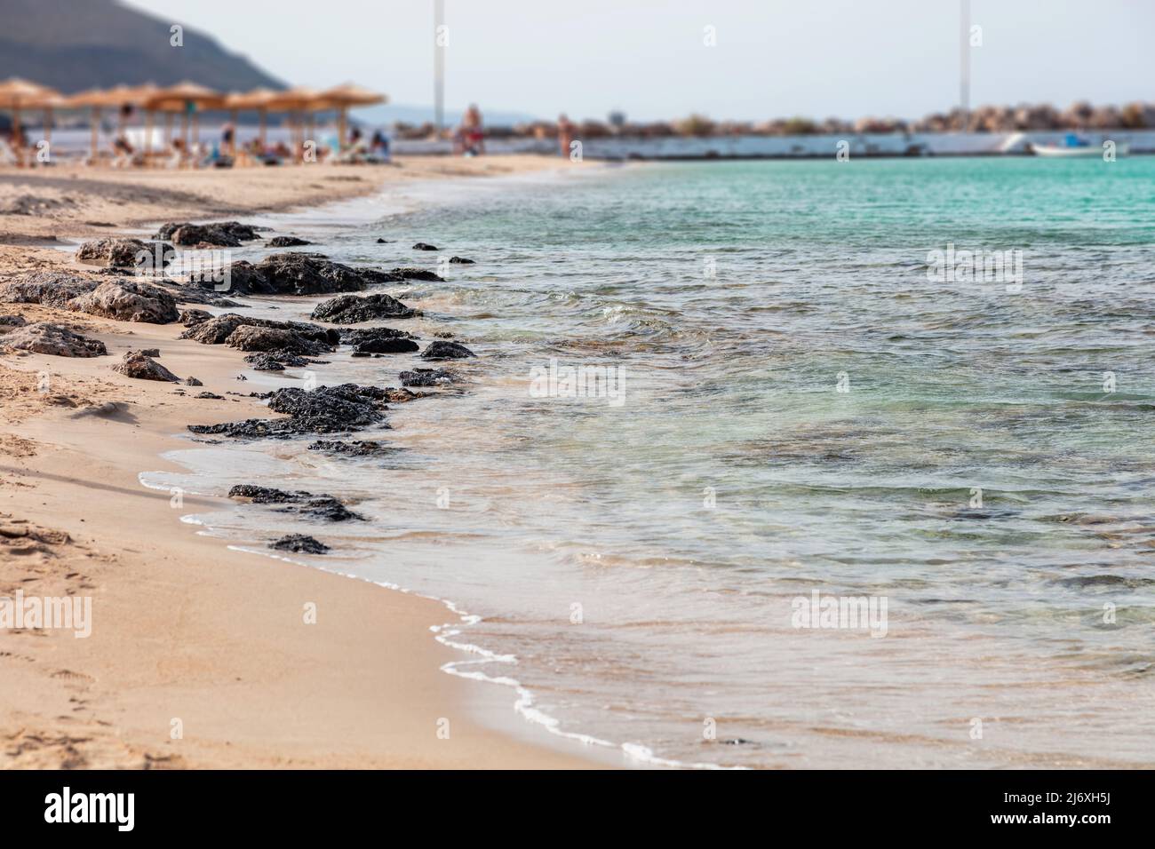 Sandstrand in Griechenland. Griechische Insel, türkisfarbenes Meerwasser, kleine Wellen auf nassem Sand, blauer Himmel, sonniger Tag, Sommerurlaub Stockfoto