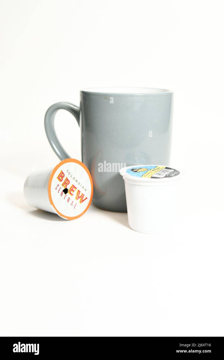 Graue Kaffeetasse und gebrauchte K-Tassen-Pads für eine Tasse, isoliert auf weißem Hintergrund Stockfoto