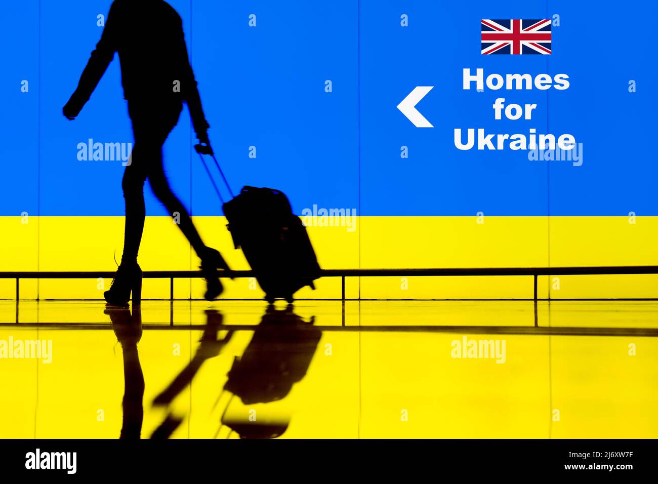 Frau, die durch den Flughafen mit der Flagge der Ukraine überdeckt ging. Häuser für die Ukraine, Russland Ukraine Konflikt Krieg, Flüchtlinge, EU, Russland Sanktionen Konzept. Stockfoto