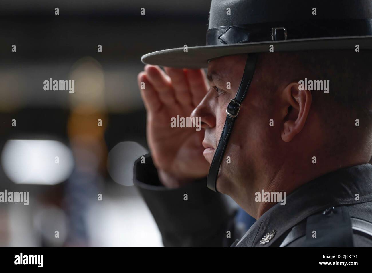 Ein Polizeikommissar der Pennsylvania State Police begrüßt, als sie die Nationalhymne beim PA State Police Memorial-Programm singen. Die Polizeitruppe P der Pennsylvania State Police in Wilkes-Barre hielt einen Gedenkgottesdienst für die Staatspolizei ab, der in den letzten 117 Jahren seines Bestehens gestorben ist. Seit der letzten persönlichen Zeremonie wurden 5 Staatspolizisten in die Liste aufgenommen. Zwei Soldaten starben nach einem Vorfall mit einem betrunkenen Fahrer in Philadelphia im März. Stockfoto