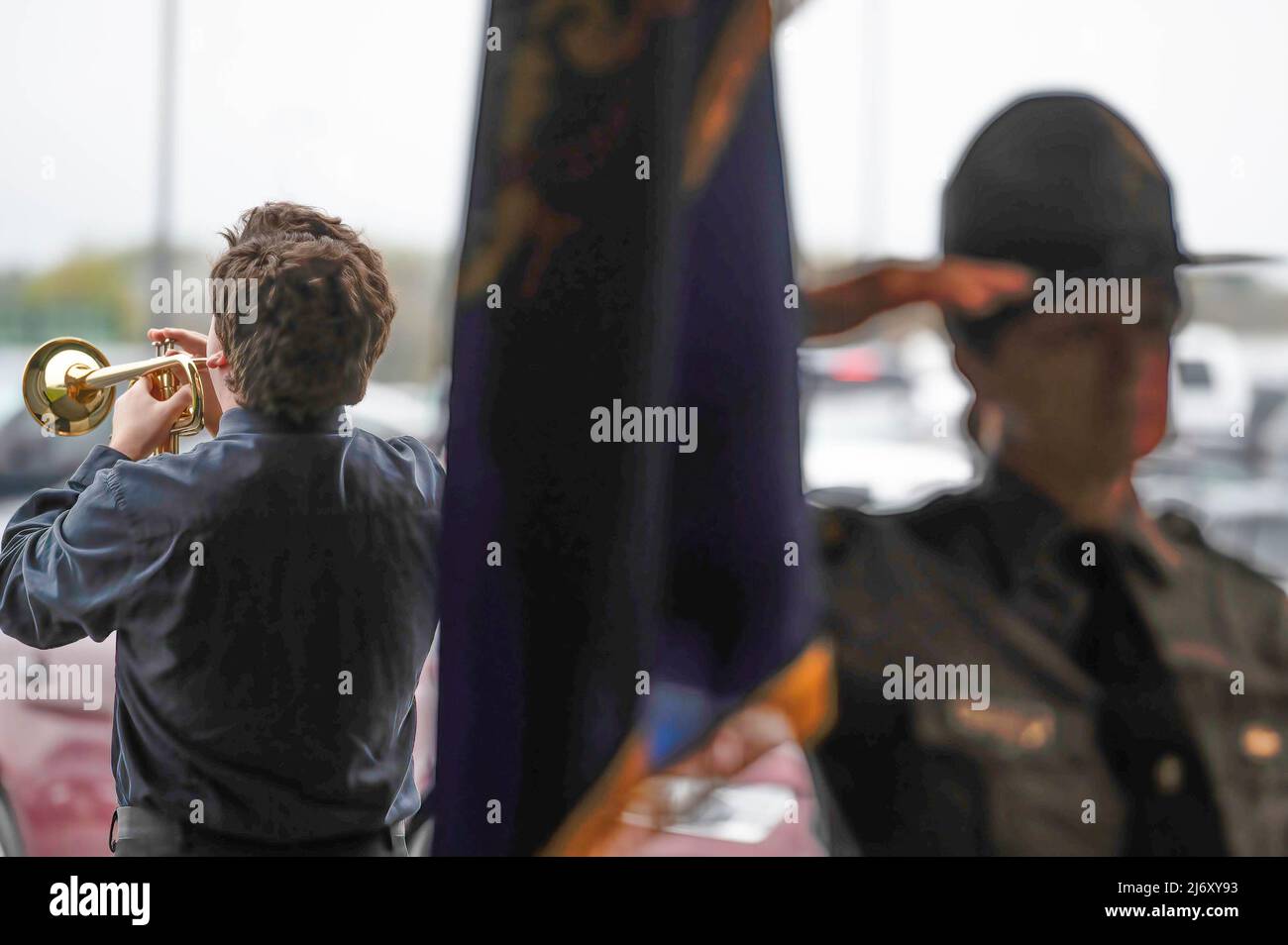 Ein Junge spielt Taps neben einem Pennsylvania State Police Trooper, der während des PA State Police Memorial Programms grüßt. Die Polizeitruppe P der Pennsylvania State Police in Wilkes-Barre hielt einen Gedenkgottesdienst für die Staatspolizei ab, der in den letzten 117 Jahren seines Bestehens gestorben ist. Seit der letzten persönlichen Zeremonie wurden 5 Staatspolizisten in die Liste aufgenommen. Zwei Soldaten starben nach einem Vorfall mit einem betrunkenen Fahrer in Philadelphia im März. Stockfoto