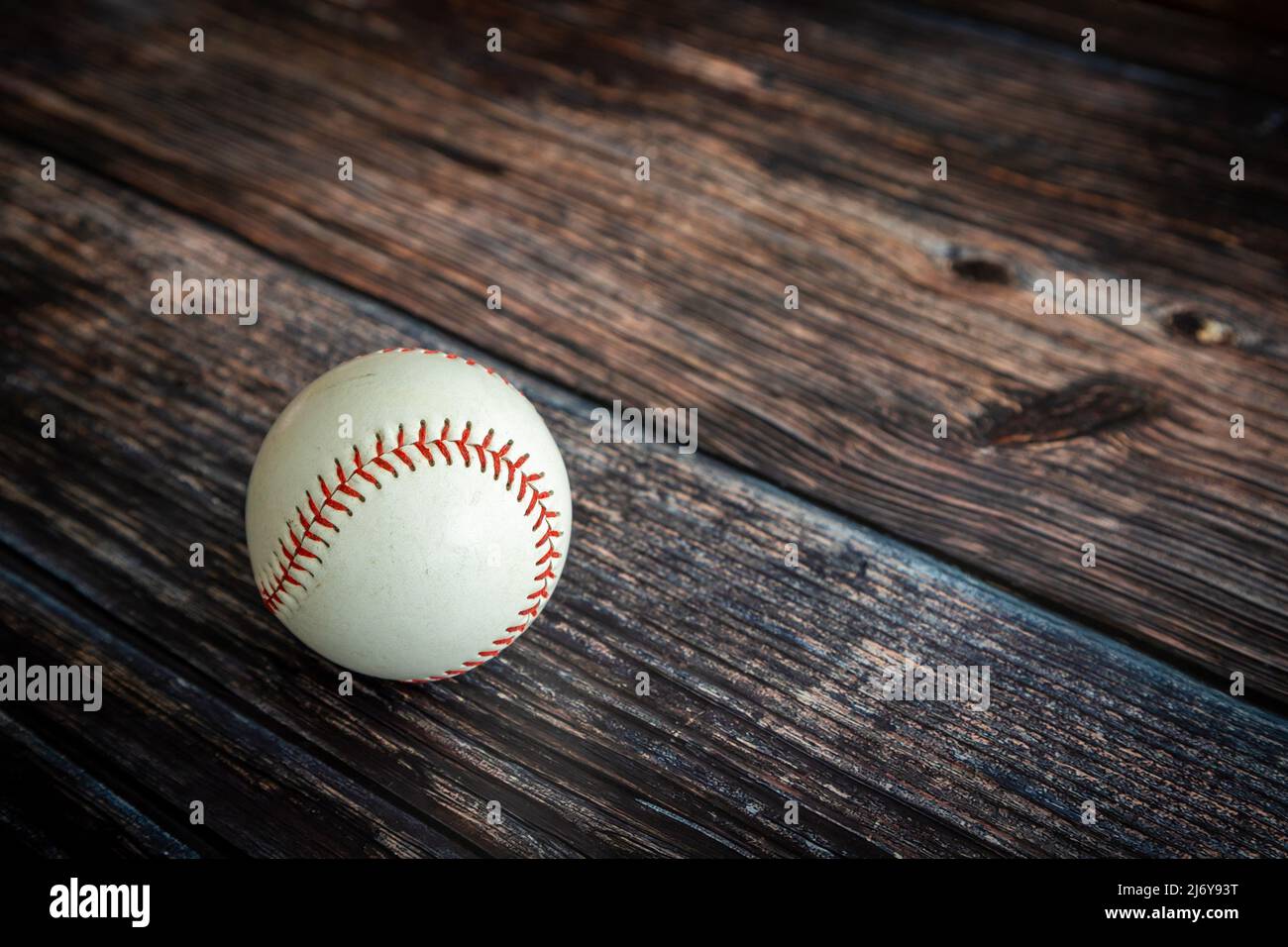 Leder-Baseballball oder Softball auf rustikalem Holzhintergrund mit Kopierfläche. Stockfoto