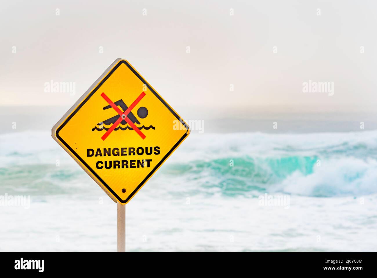 März 2022:Ein gefährliches Stromschild am Bronte Beach in Sydney, Australien an einem Wochenende voller wilder Brandung und Nebel am frühen Morgen, die einen grauen Hintergrund erzeugen Stockfoto