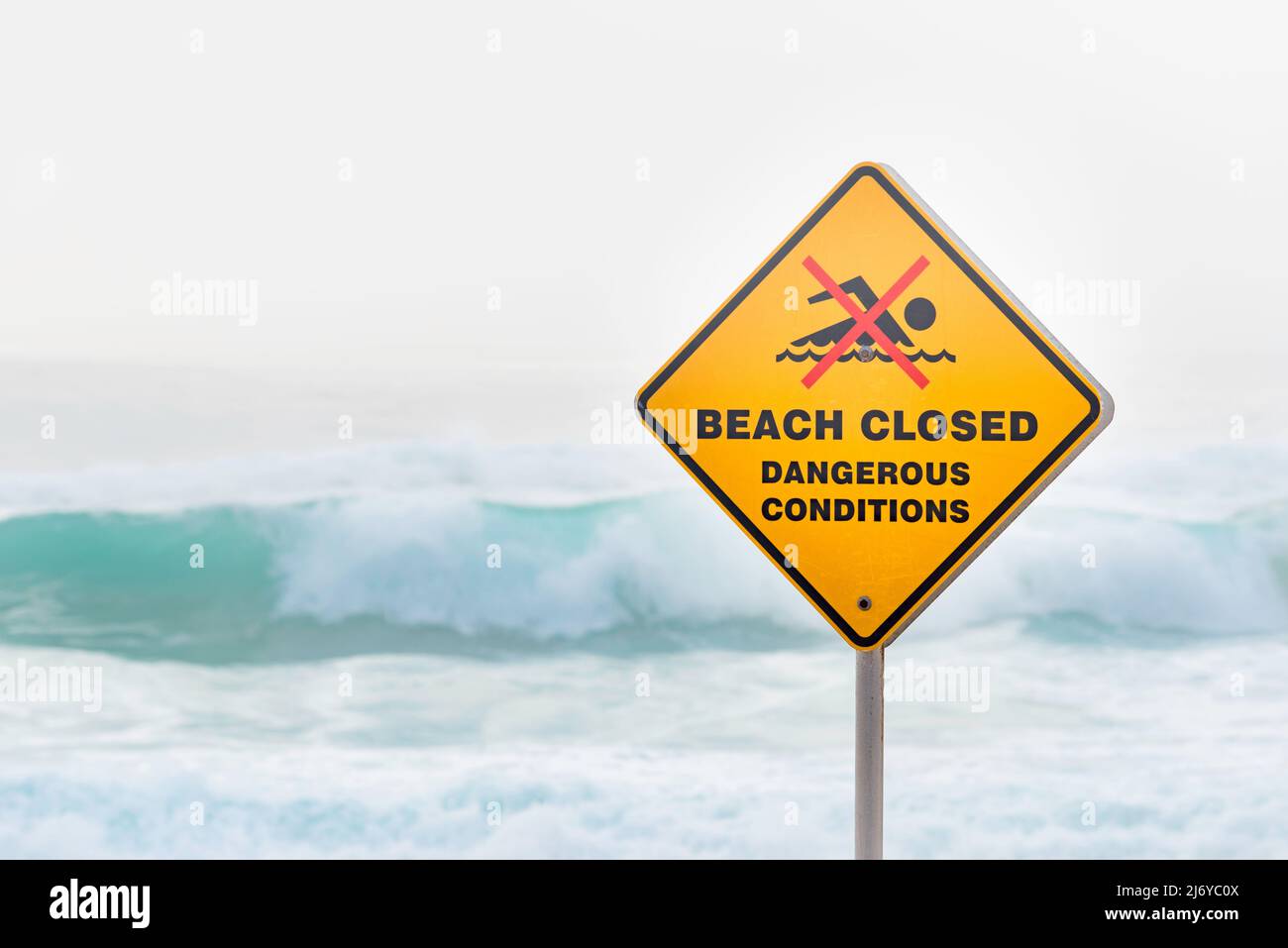 März 2022:Ein Warnschild am Bronte Beach in Sydney, Australien, an einem Wochenende voller wilder Brandung und Nebel am frühen Morgen, die einen grauen Hintergrund erzeugen Stockfoto