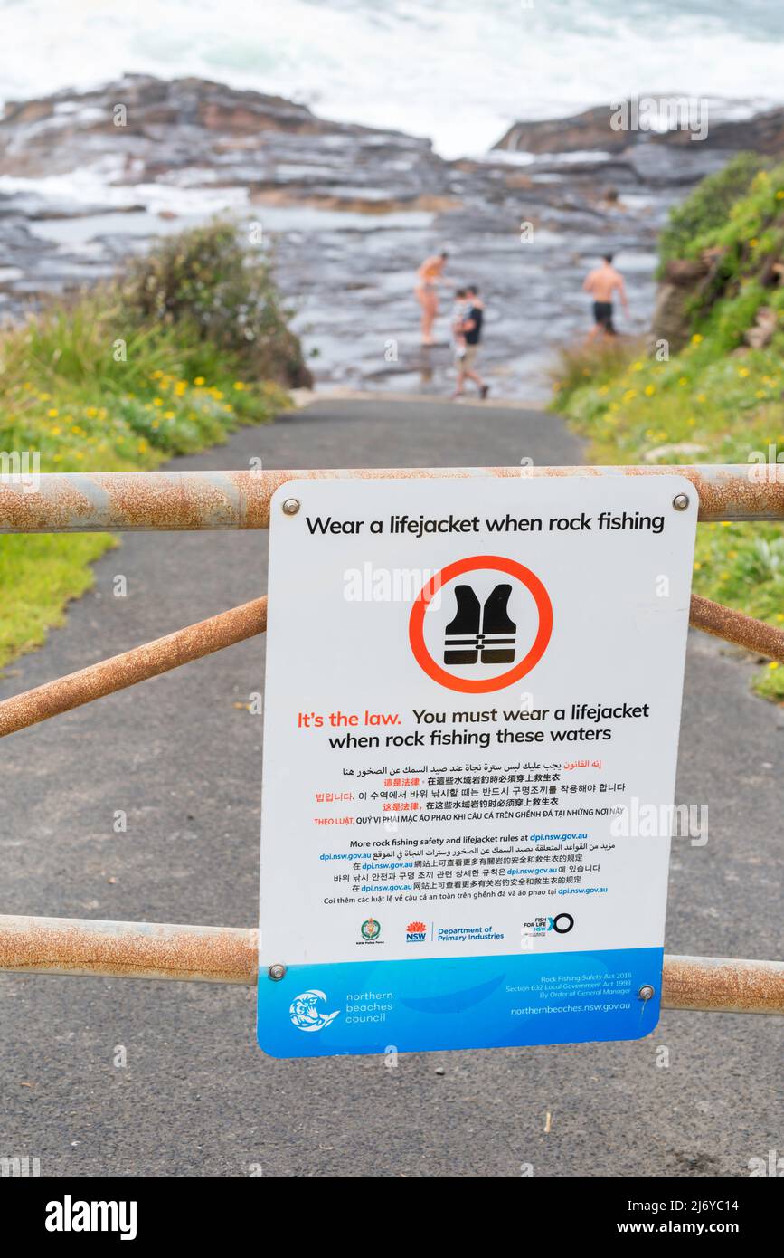 Ein Schild, das Menschen, insbesondere Fischer, per Gesetz warnt, dass sie in diesem Felsenanglergebiet am South Curl Curl Beach, Sydney, Schwimmwesten oder PFD's tragen müssen Stockfoto