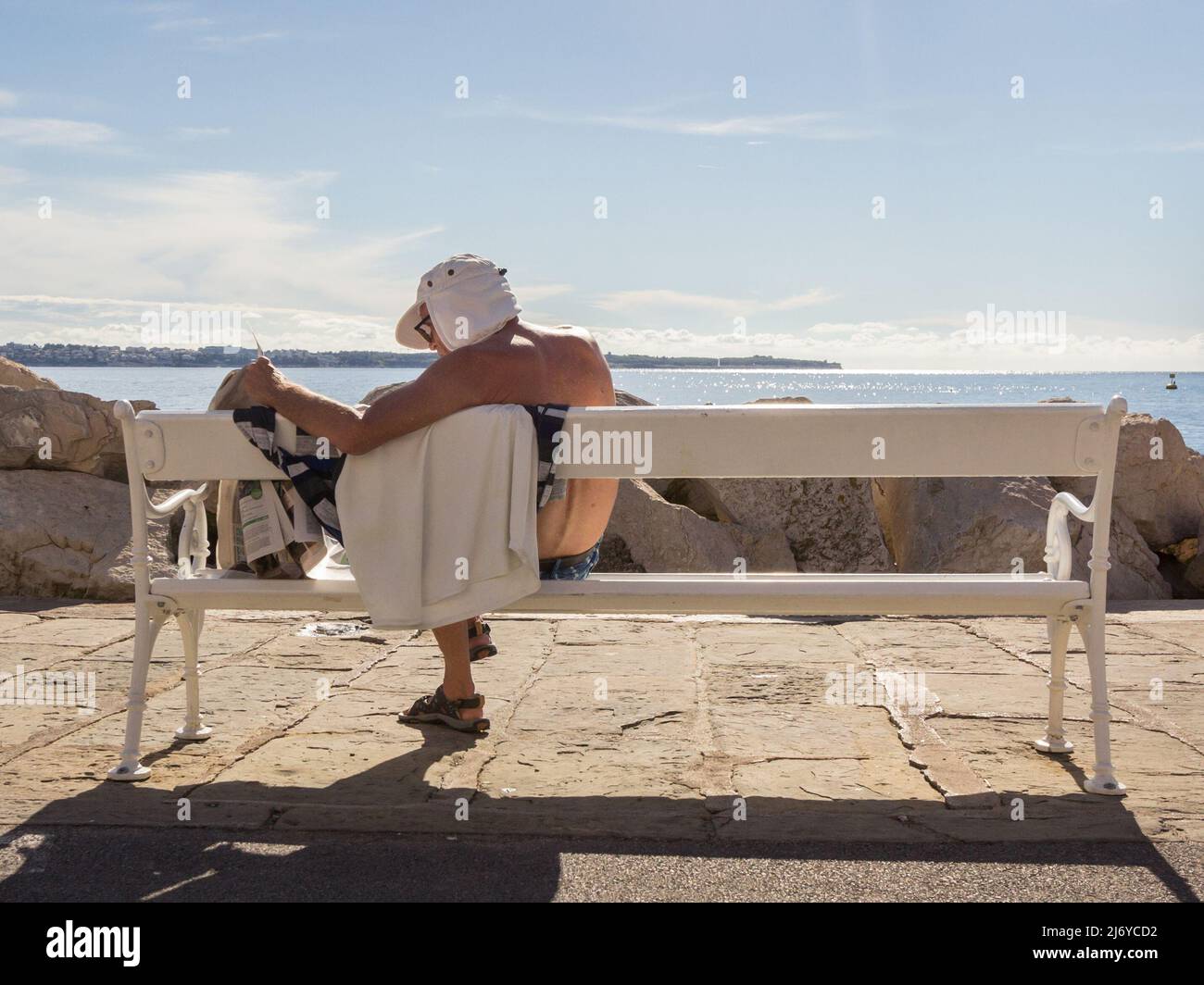 Bild eines alten Mannes, der in der slowenischen Stadt Piran, in Slowenien, an einem Strand vor der adria, ein Tagebuch der slowenischen Presse liest. Stockfoto
