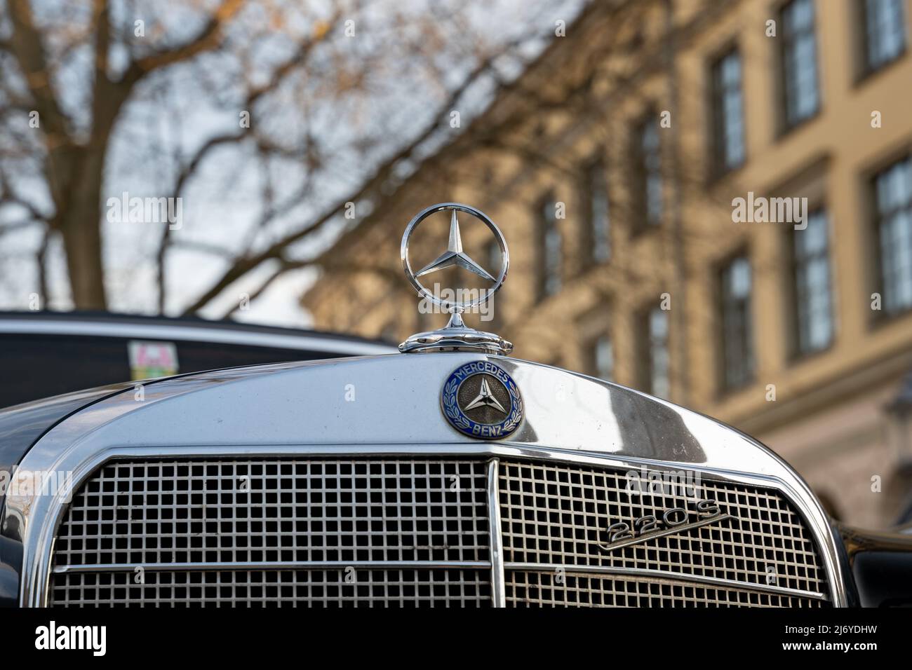Mercedes-Benz W111 220 S Frontemblem eines schwarzen Autos. Klassisches deutsches Auto mit glänzendem Chrom-Frontgrill und einem Kühlerfigur. Stockfoto