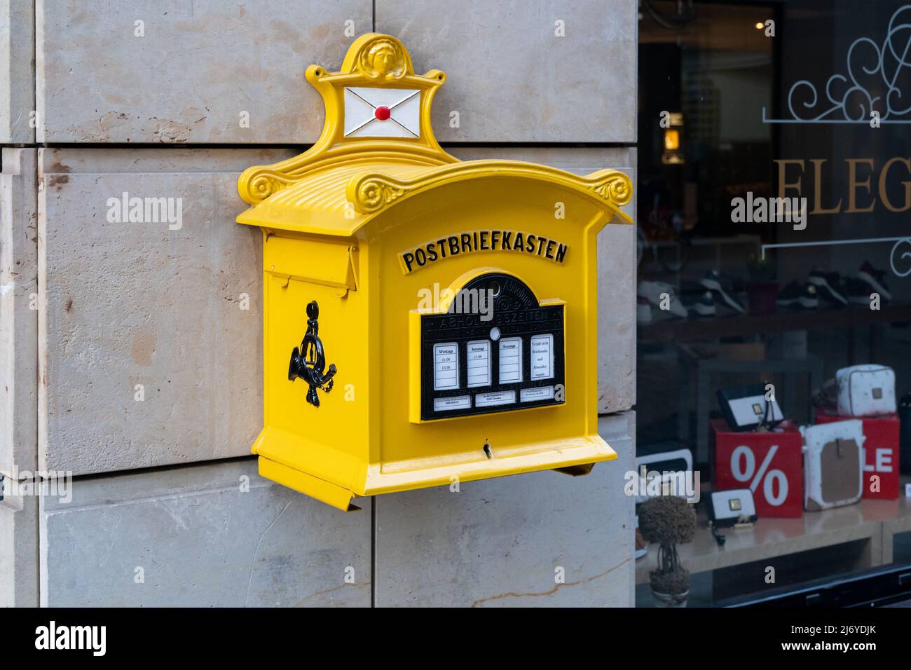 Alte gelbe Briefkasten der deutschen Post. Ein Briefkasten zum Versenden von Karten und Briefen an eine Sandsteinwand. Stockfoto