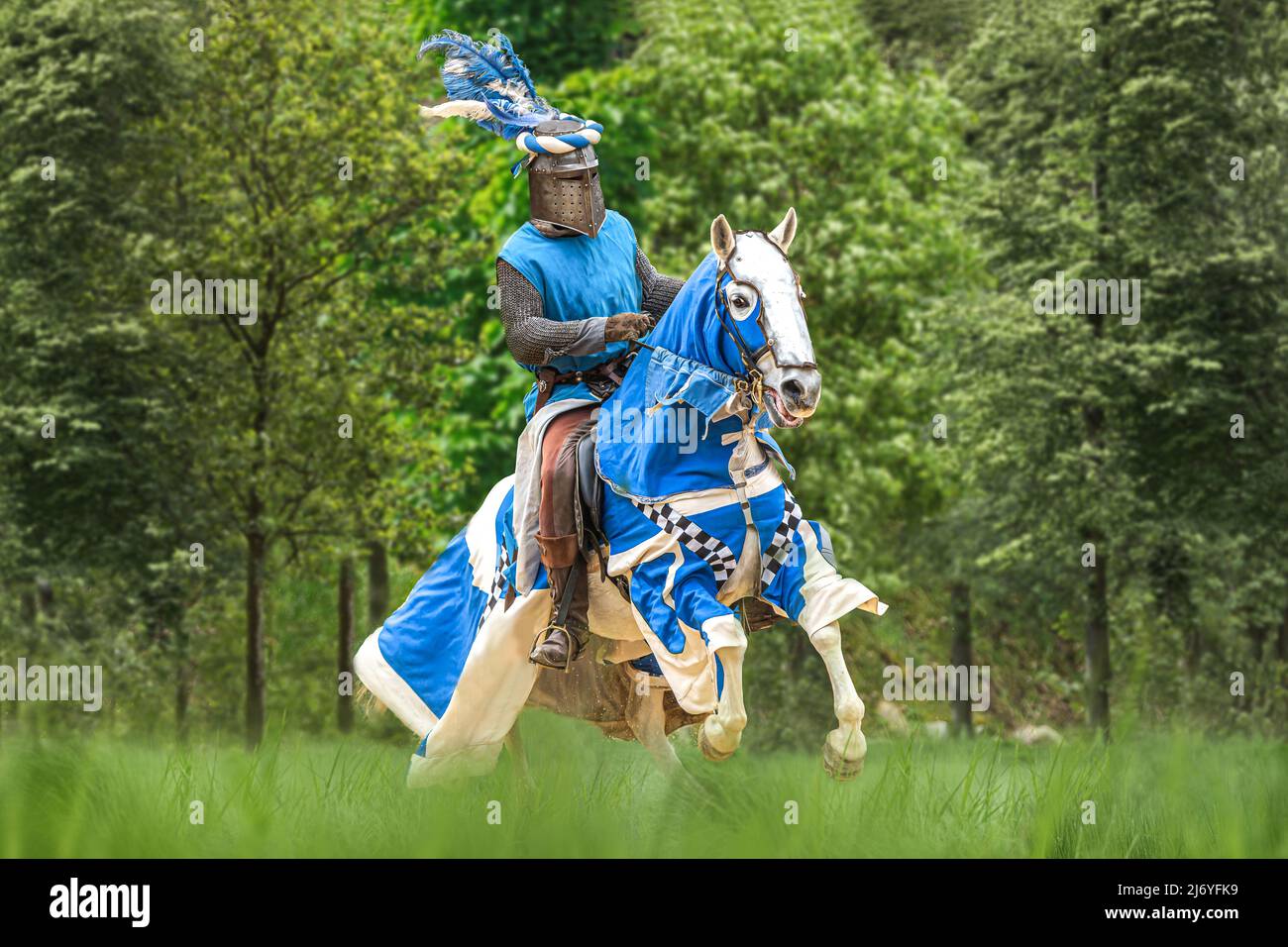 Porträt eines mittelalterlichen Ritters, der im Frühling auf einer Wiese im Freien auf seinem Pferd reitet Stockfoto