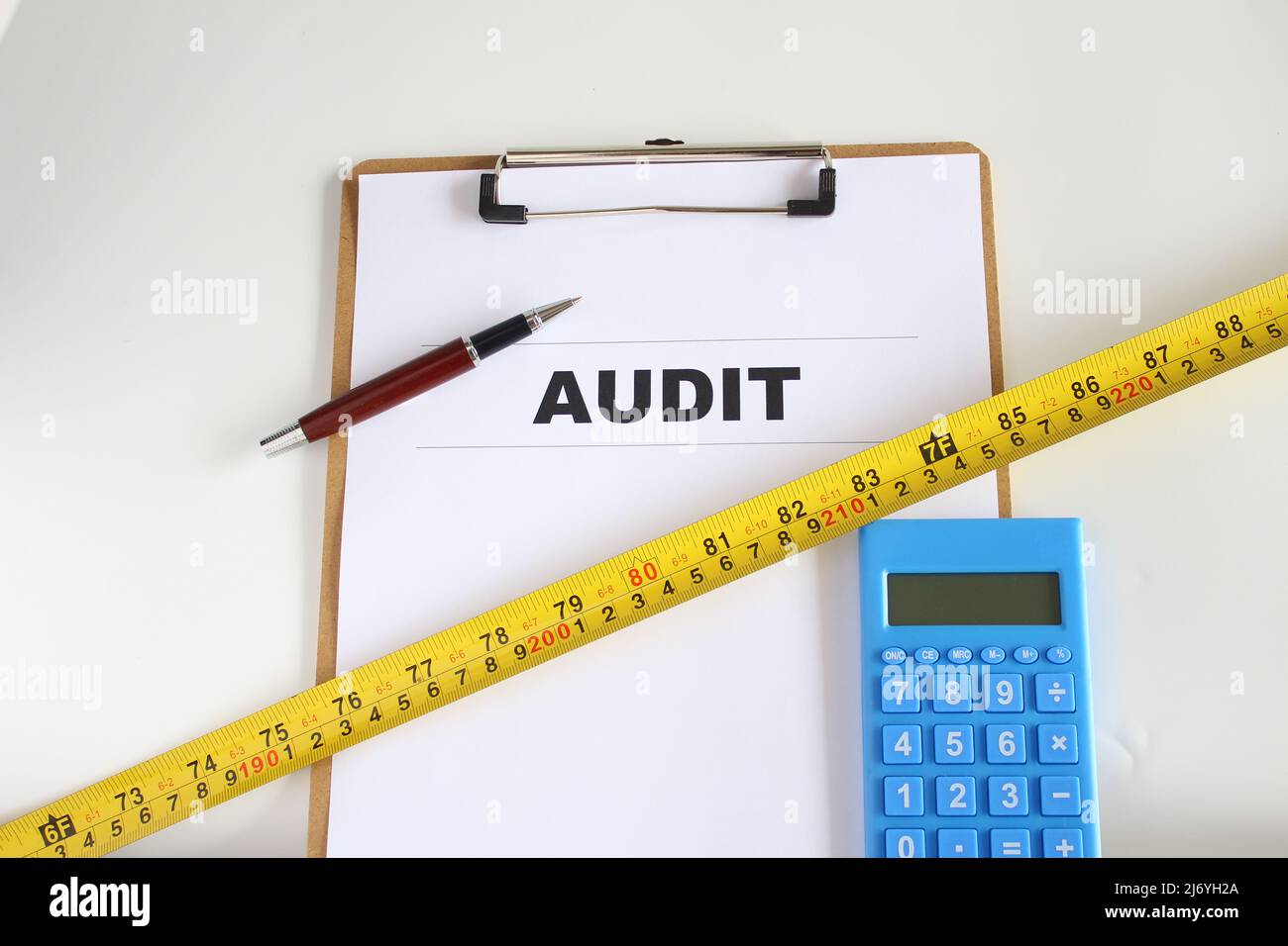 Audit-Wort auf Arbeitspapier mit Stift, Maßband und Rechner. Geschäftsverbesserungskonzept. Isolierter Hintergrund. Stockfoto