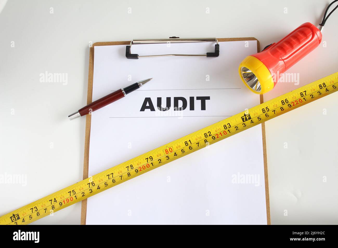 Audit-Wort auf Arbeitspapier mit Stift, Maßband und Rechner. Geschäftsverbesserungskonzept. Isolierter Hintergrund. Stockfoto