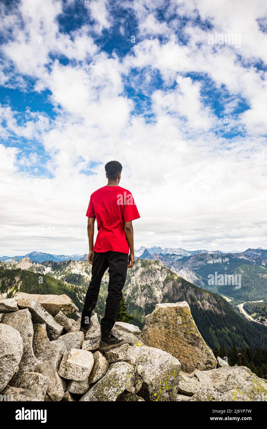 Ein junger Mann auf dem Granite Peak in den Washington Cascades mit Blick auf die Aussicht. Stockfoto